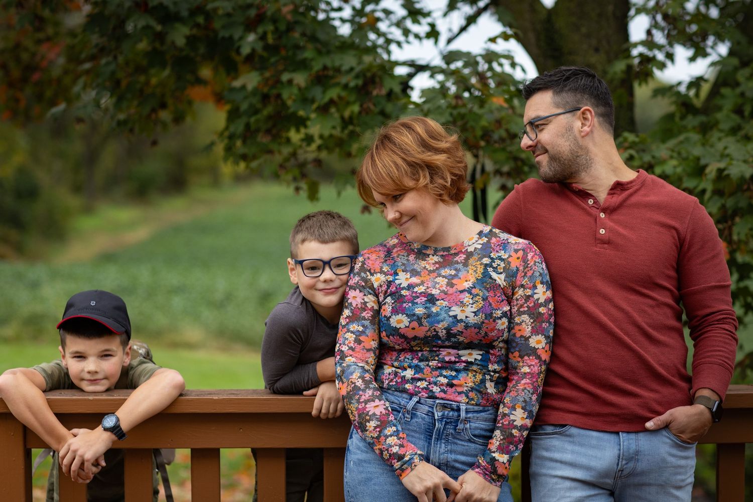 Family relaxing together on a wooden bench in a park setting during autumn.