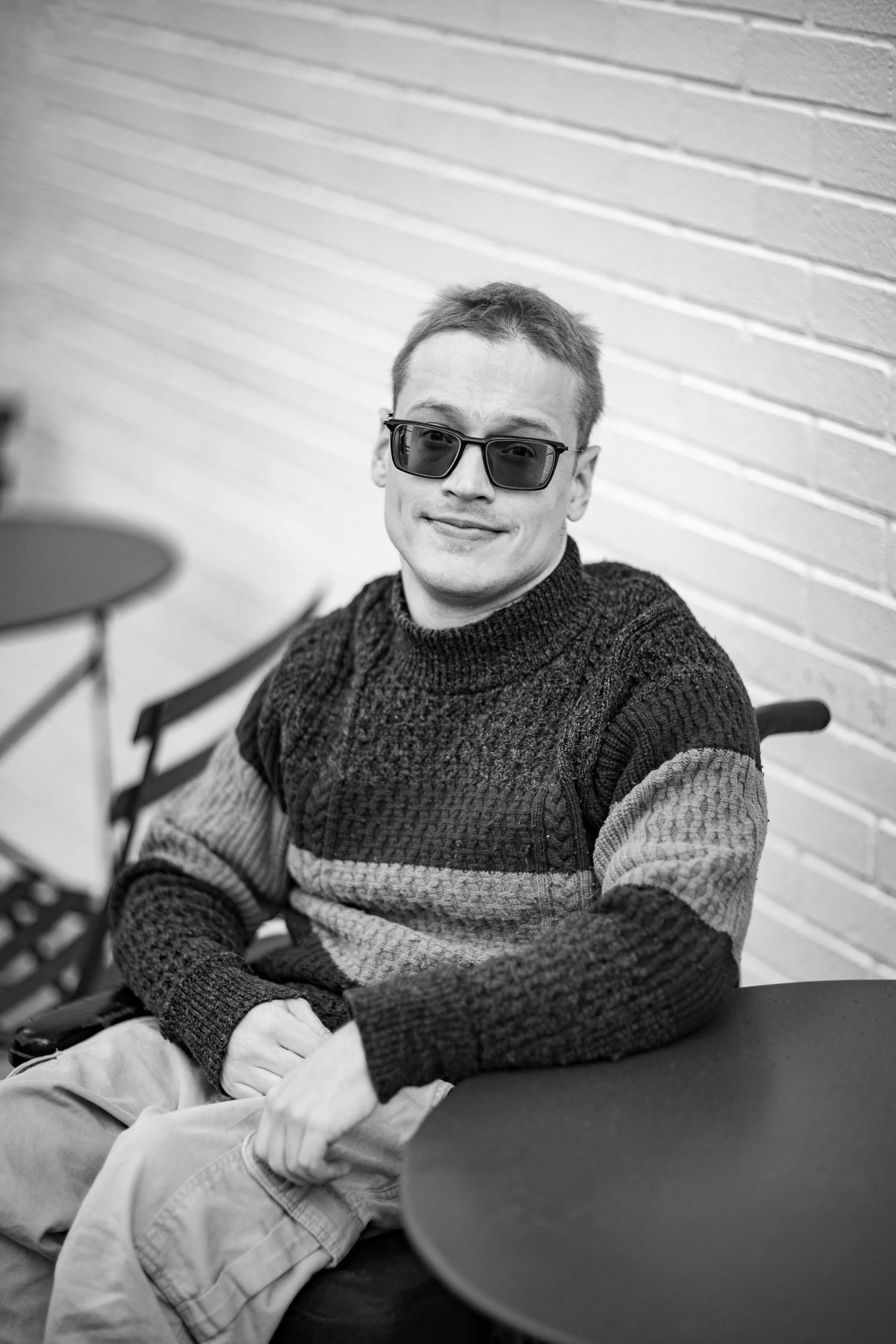 Black and white photo series showing a person in a dark knit sweater seated at a table with sunglasses.