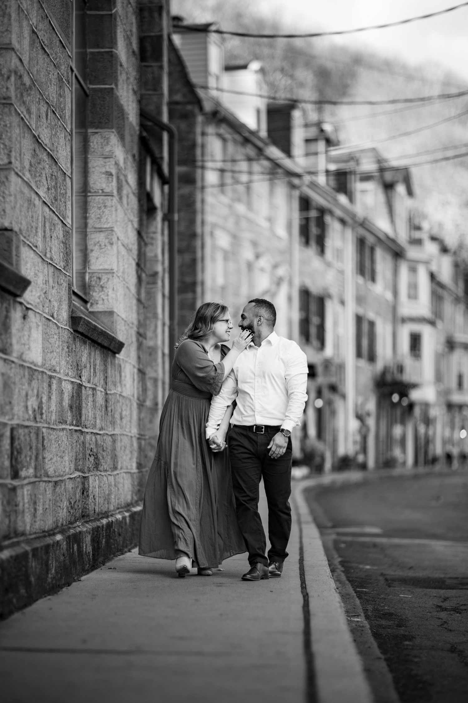 Black and white street photography series showing couple embracing against stone building wall.