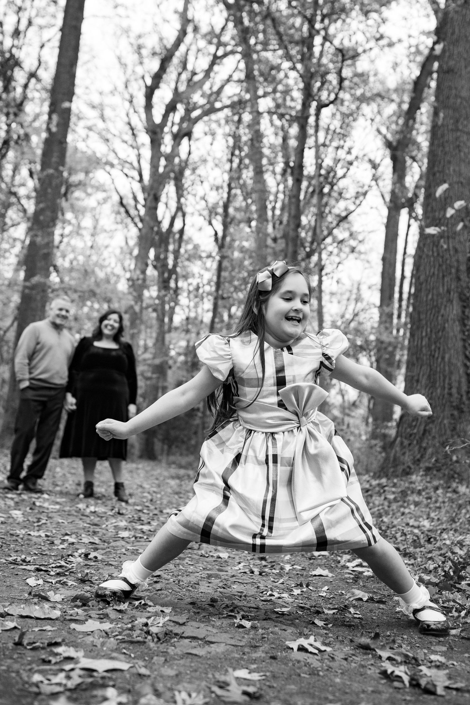 Black and white photos capturing joyful movement and dancing in a forest setting.