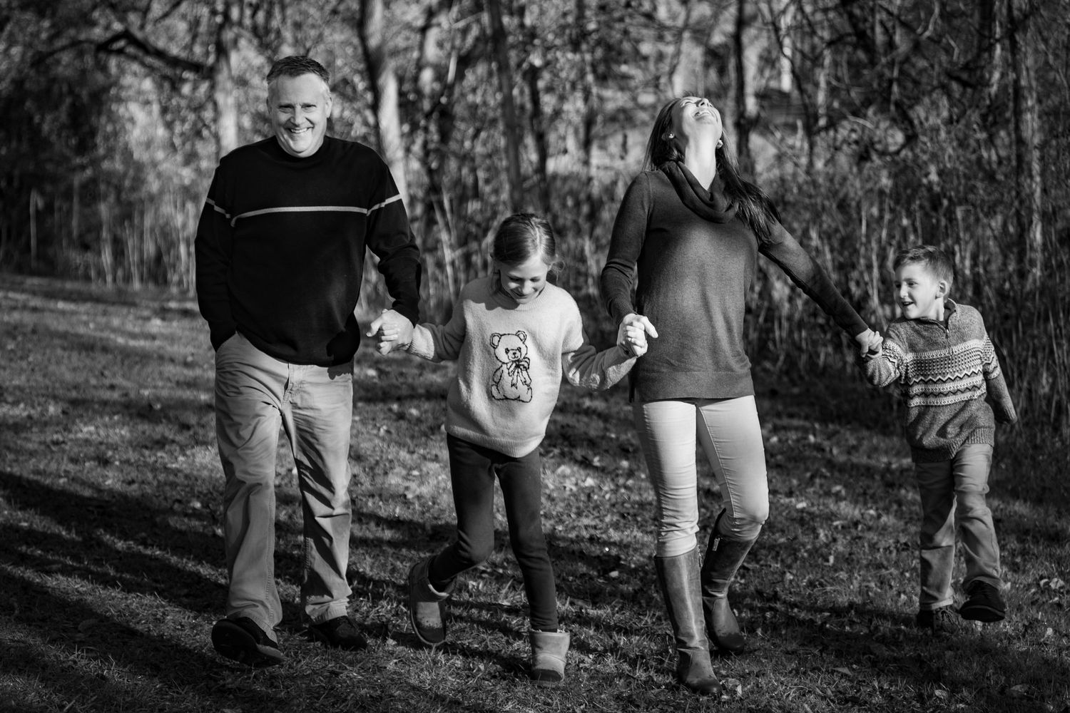 A sequence of black and white photos showing people walking together through a wooded area in casual attire.
