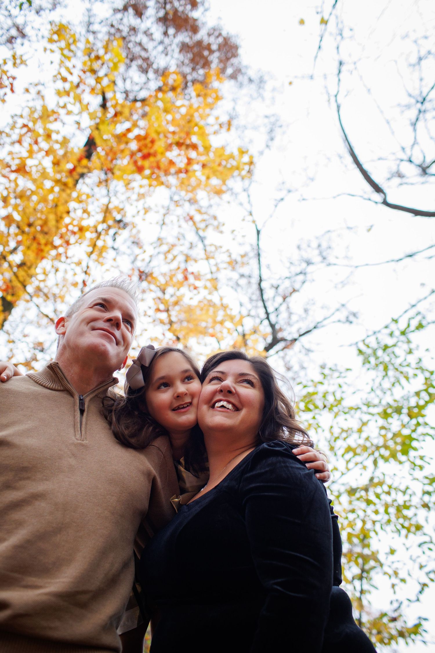 A family shares a joyful moment together against a backdrop of vibrant fall foliage.
