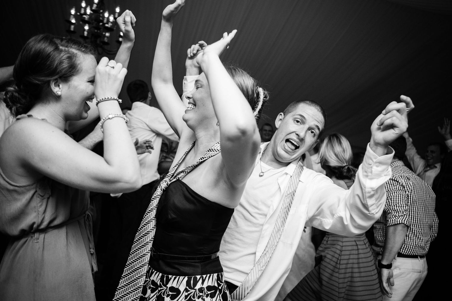 A group of wedding guests dancing enthusiastically and joyfully at a reception celebration.