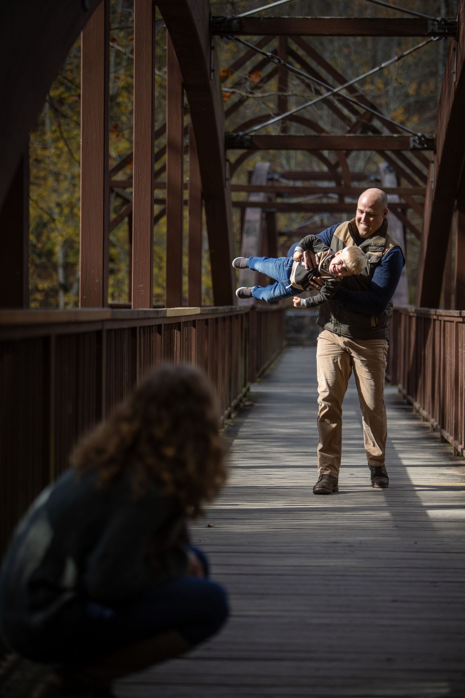 A sequence of photos shows a person in casual attire performing a backbend on a wooden bridge walkway.