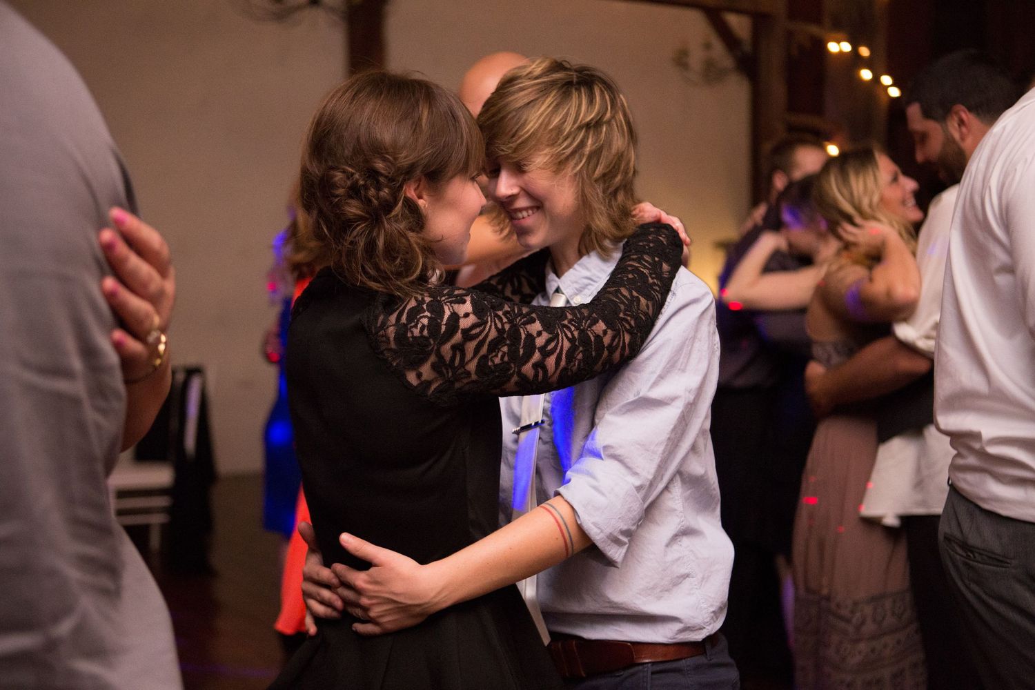 A couple shares an intimate slow dance together at a festive indoor reception.