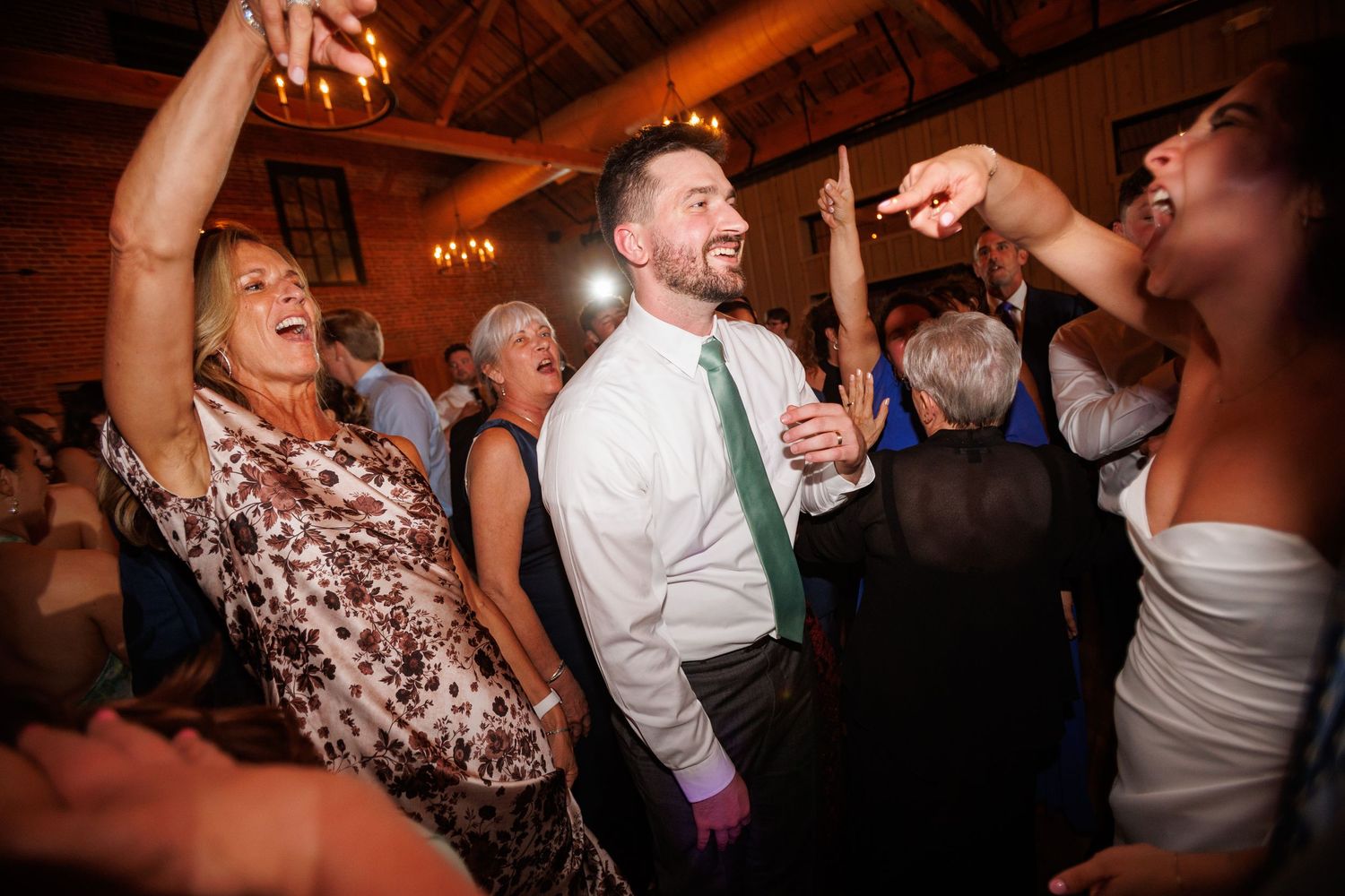 Guests dancing and smiling joyfully on a wedding reception dance floor.