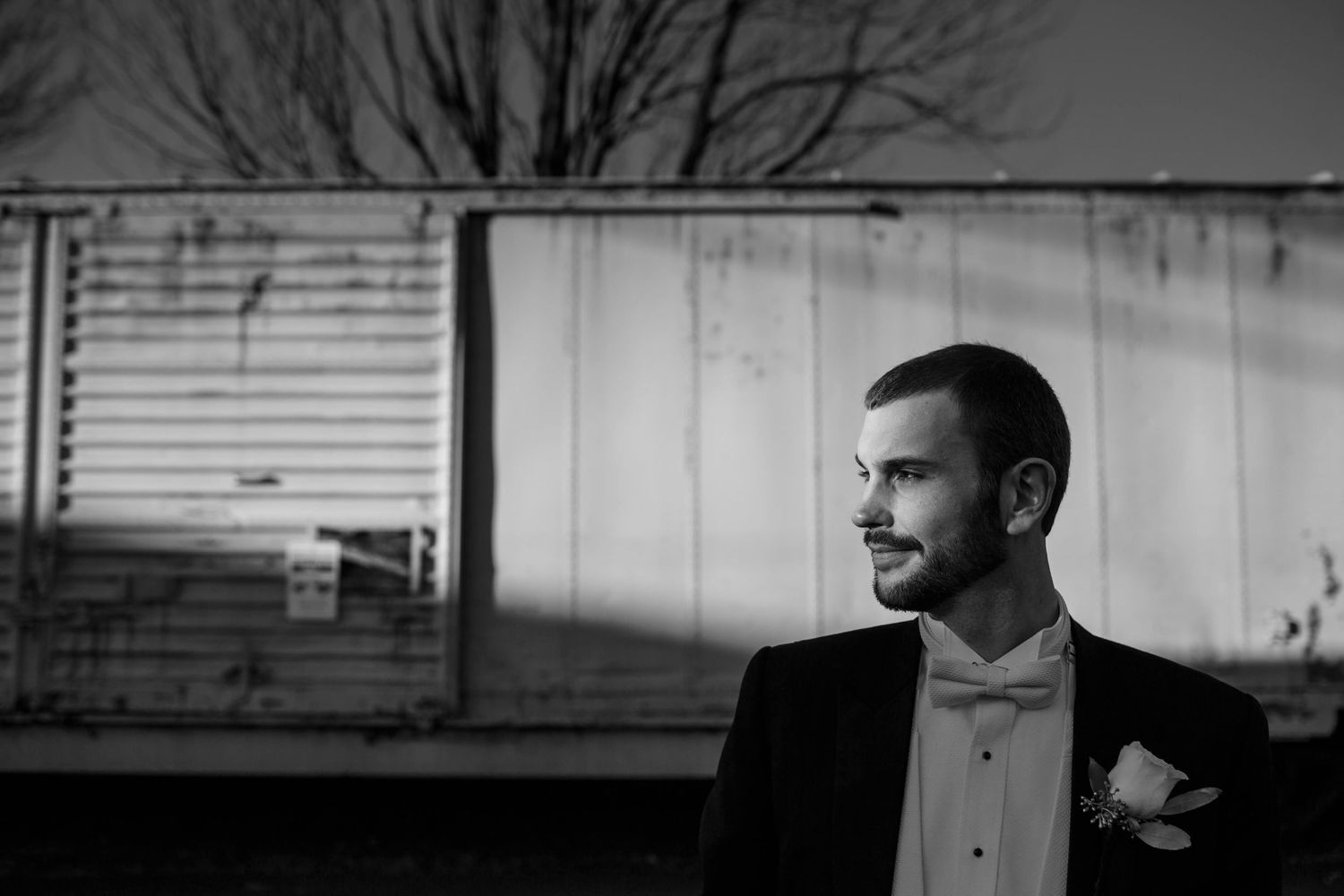 Dramatic black and white profile portrait of groom in formal attire.