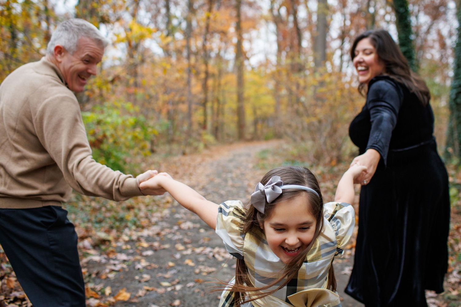 A couple shares a joyful moment together during an autumn engagement photoshoot in a wooded park setting.