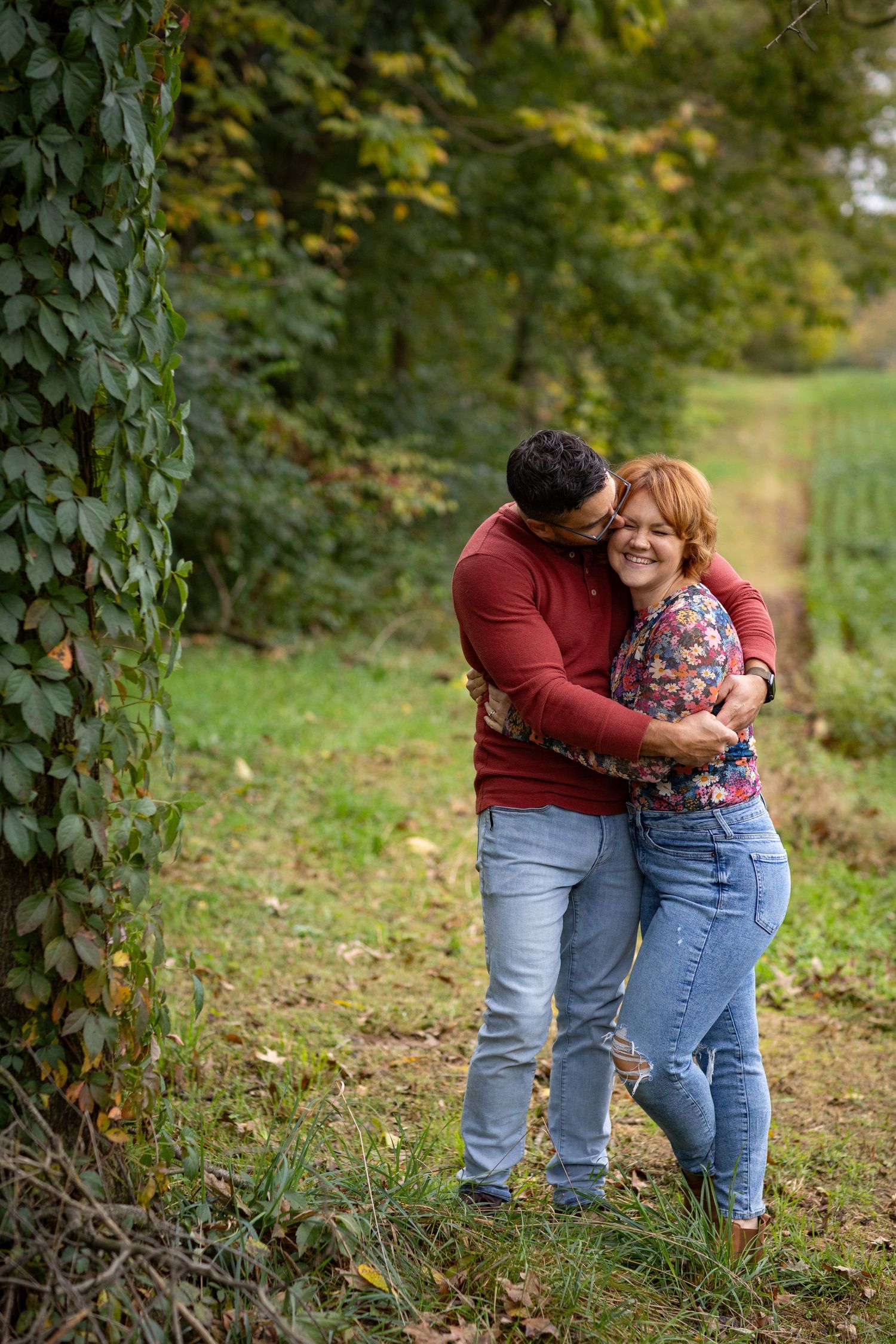 A couple shares an intimate moment outdoors surrounded by greenery.