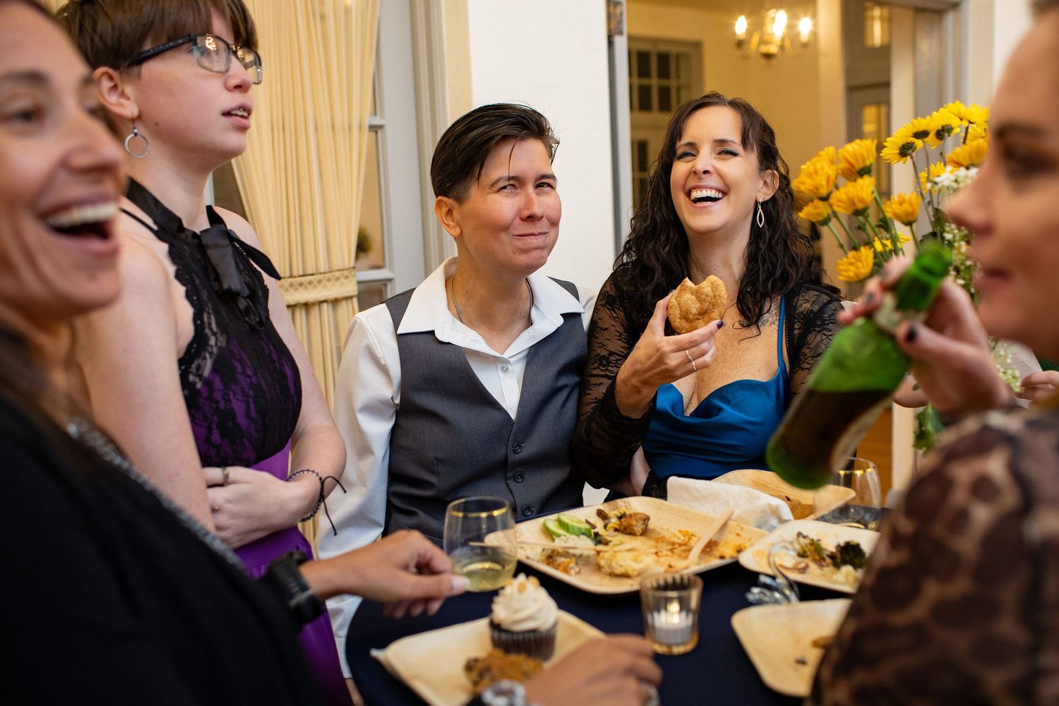 Wedding reception guests enjoying dinner and conversation at an elegant table setting.