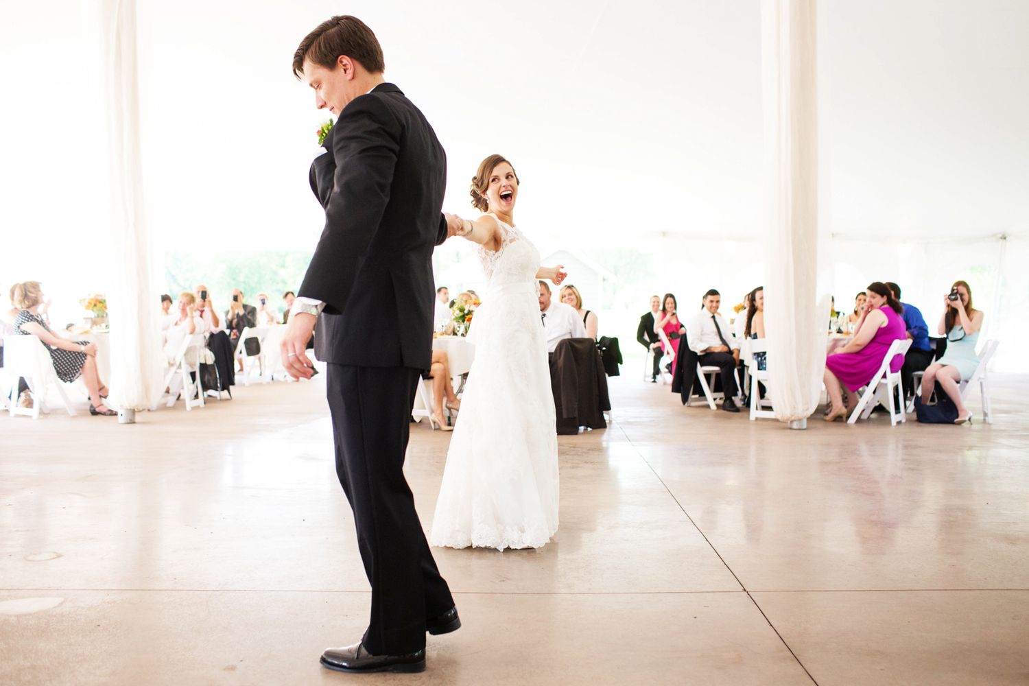 A first dance for a bride and groom iin a large white tent
