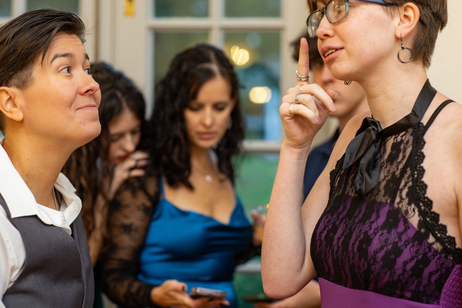 People engaged in animated conversation at a social gathering with warm lighting and festive atmosphere.