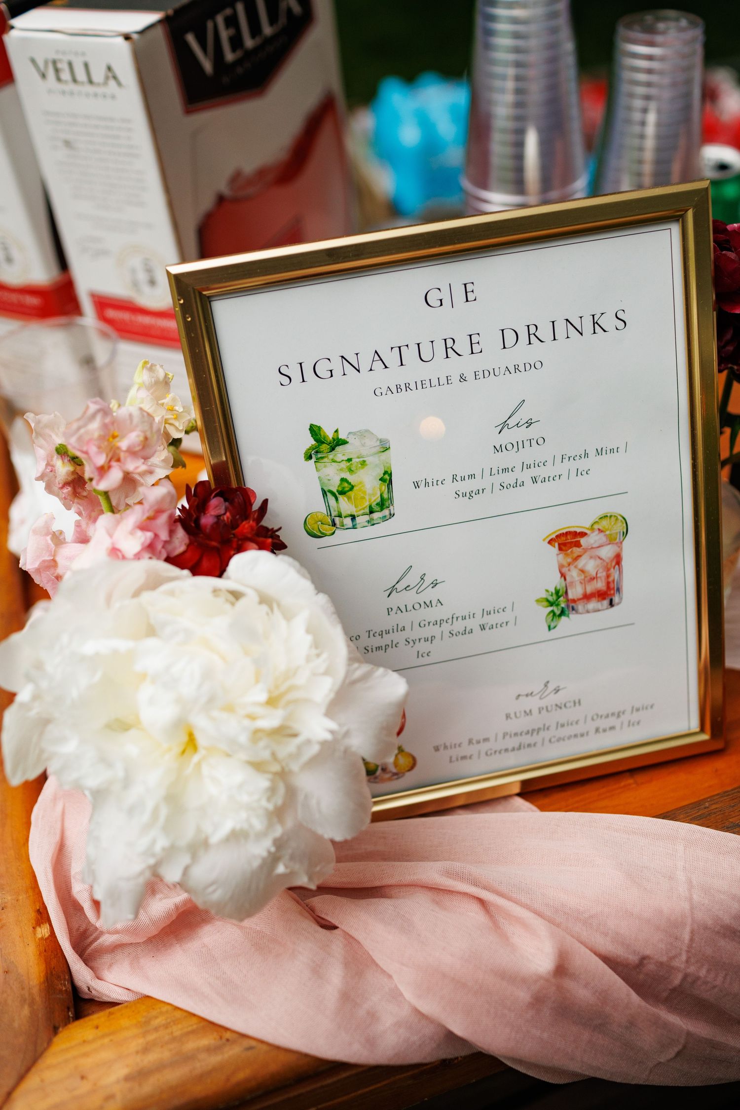 Gold-framed signature drinks menu for Gabrielle and Eduardo wedding reception with floral decor.