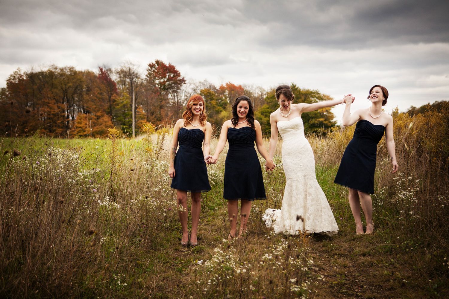 a bride and her bridesmaids walking in a field