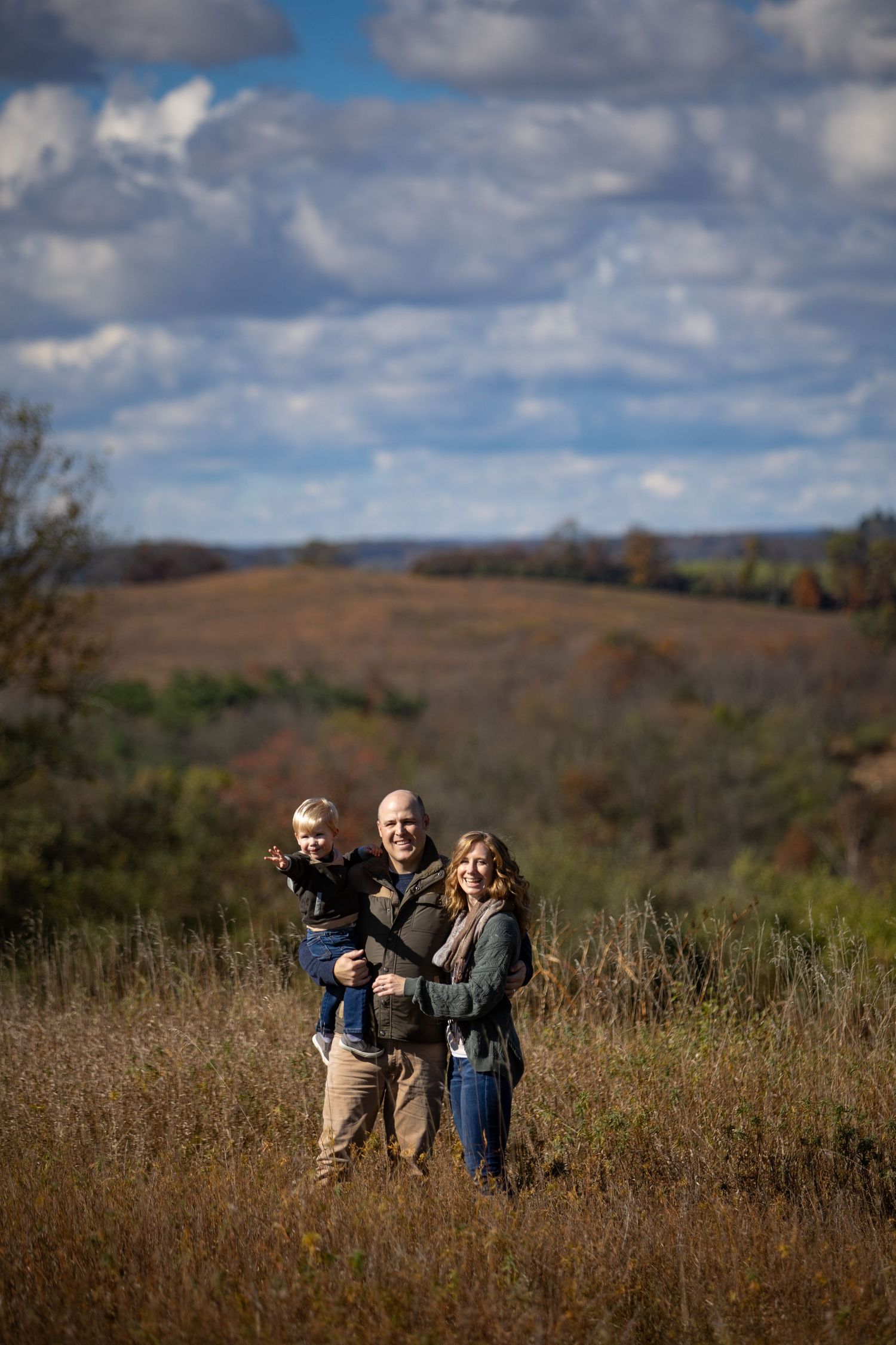 People enjoying a sunny autumn day in a golden prairie field with rolling hills and cloudy blue sky in the background.