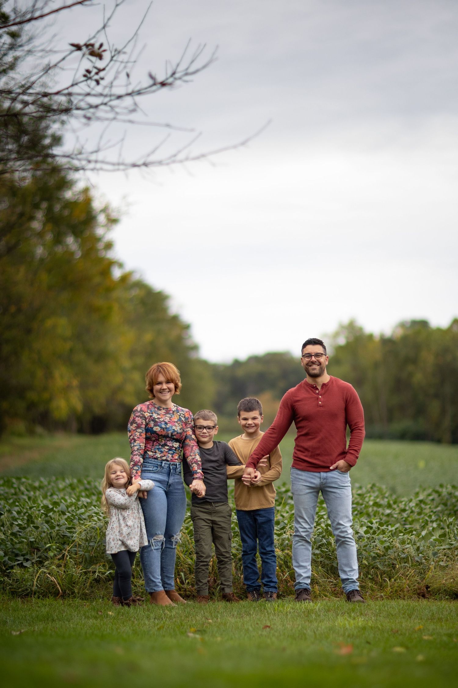 A group poses together in a green field on an overcast fall day.