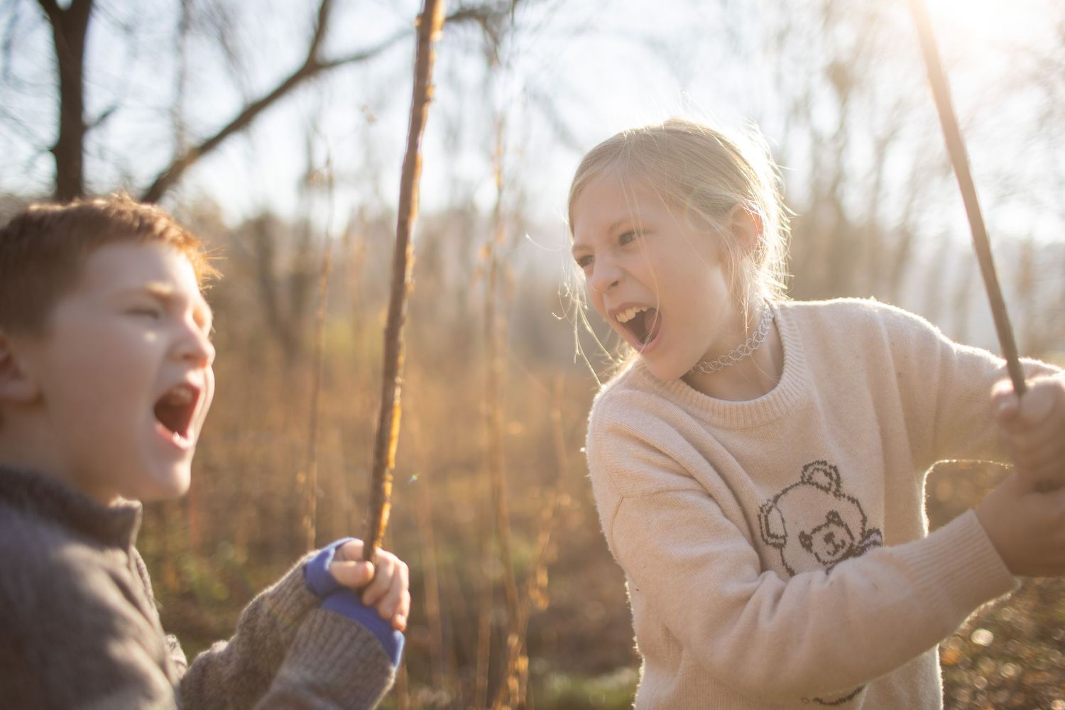 Children playing outdoors in a park during golden hour sunlight on an autumn afternoon.