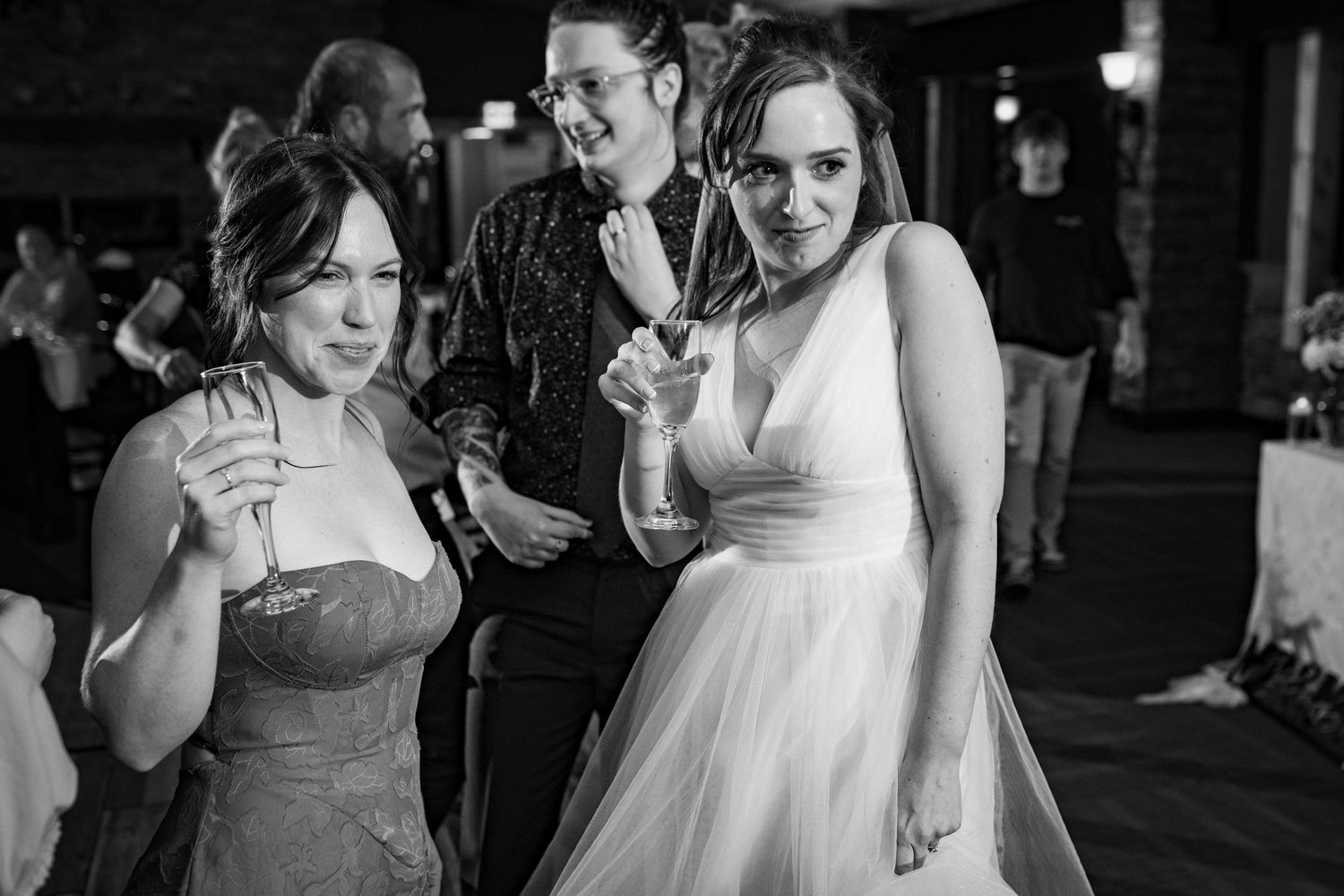 Bride and bridesmaid dancing and celebrating at a black and white wedding reception.