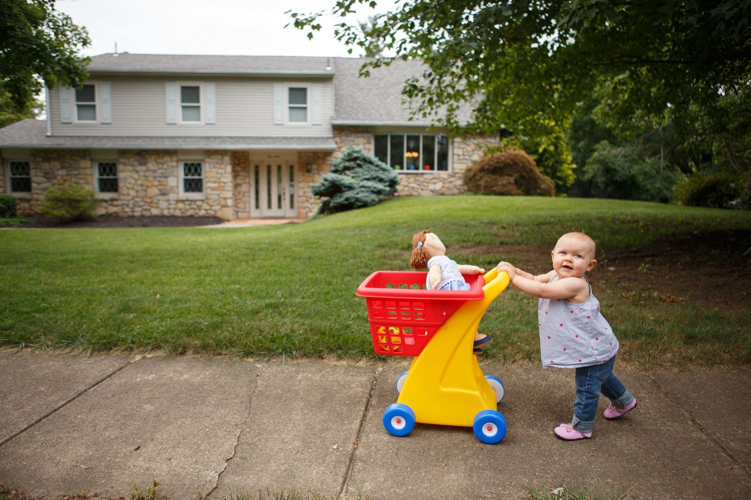 A collection of images showing toddlers playing and pulling red and yellow wagons on a driveway.