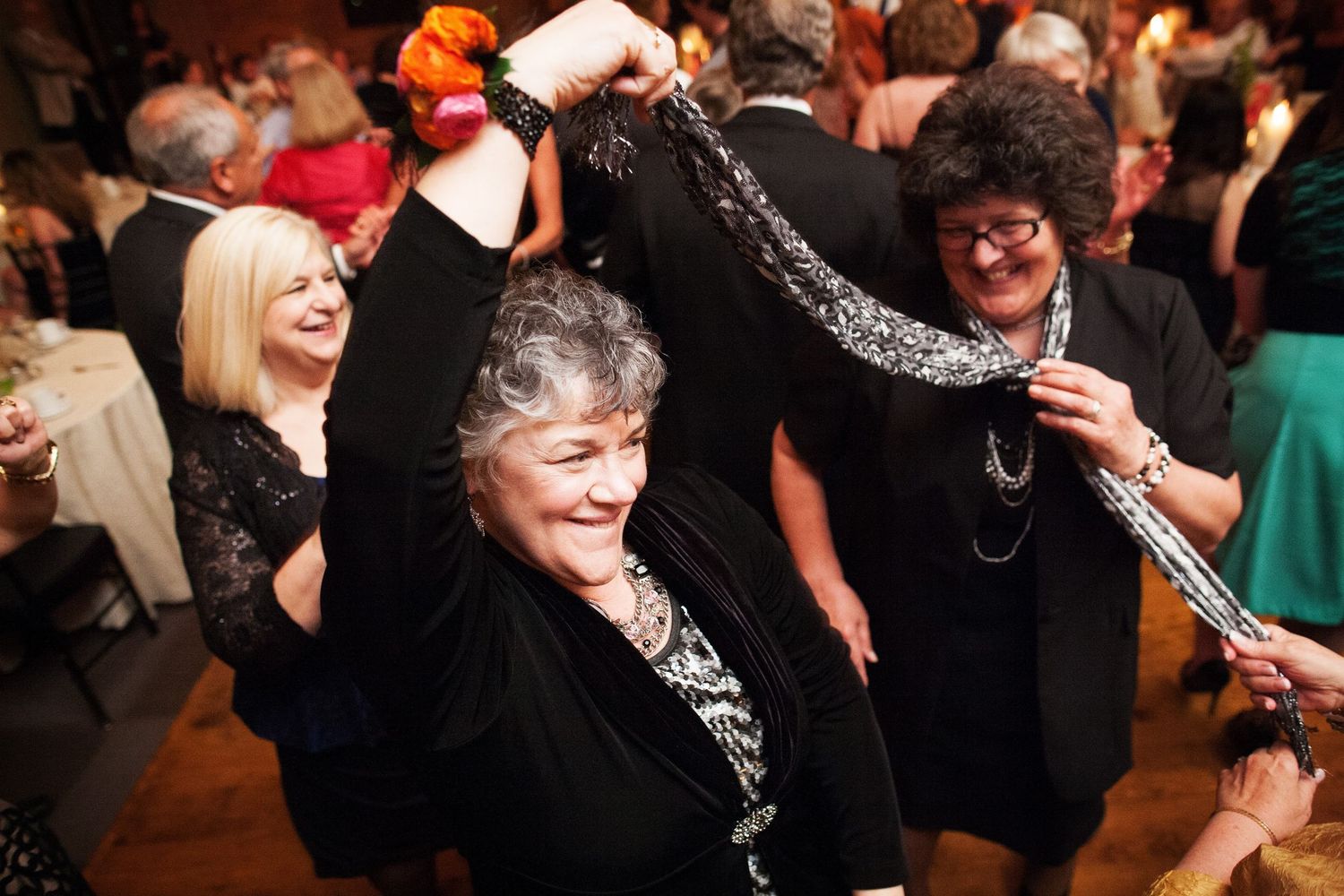 A lively crowd enjoying dancing and celebration at an indoor party event with festive energy.