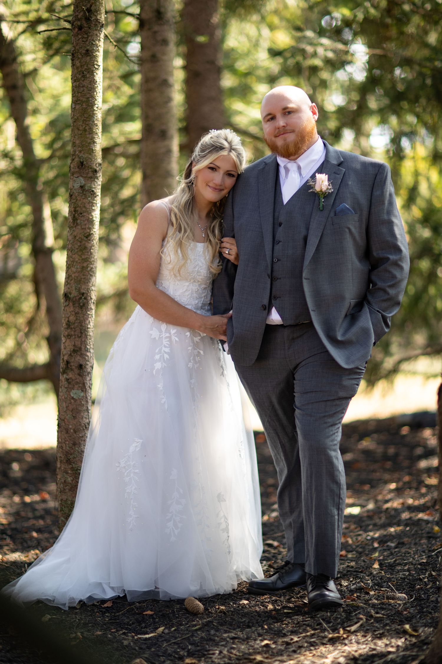 A couple poses together in a wooded forest setting during their outdoor wedding photo session, captured in multiple angles.