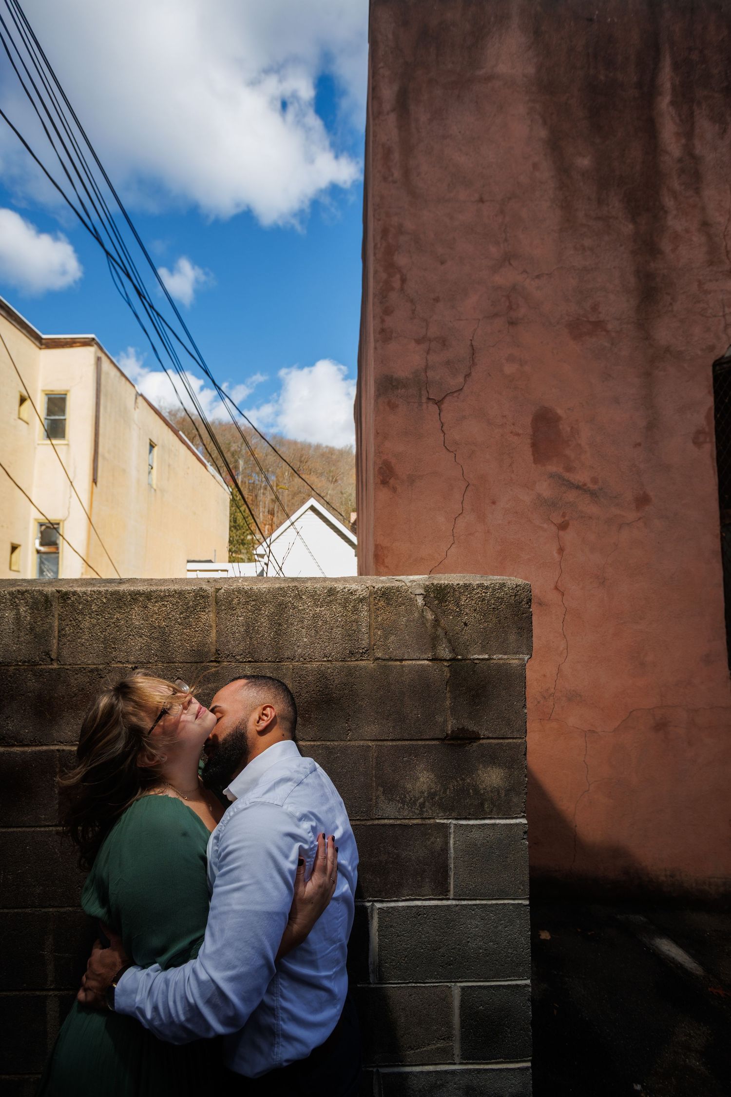 A series of intimate moments captured against an urban wall backdrop under blue skies.