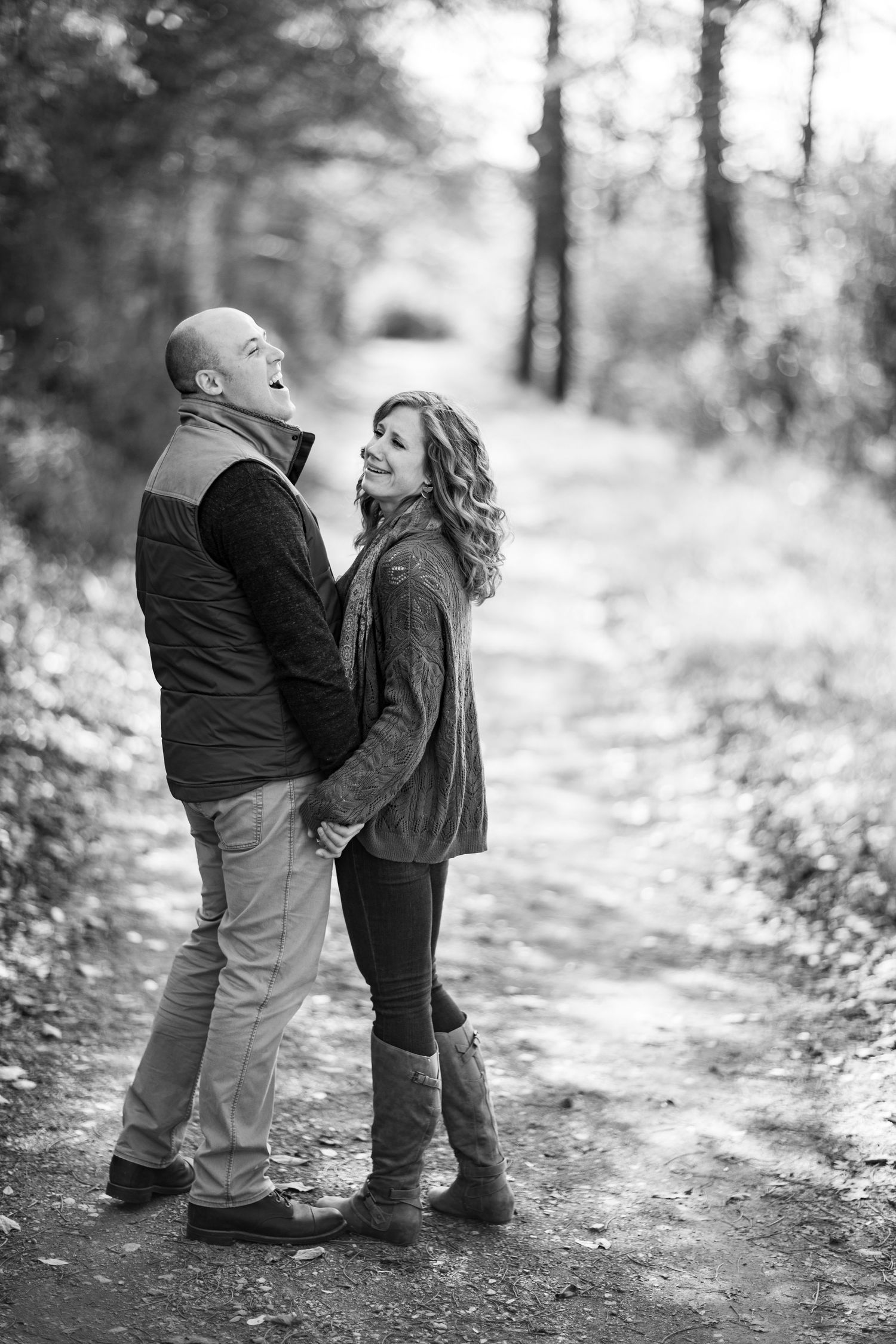 Black and white photo series of two young children sharing a sweet moment on a wooded path.