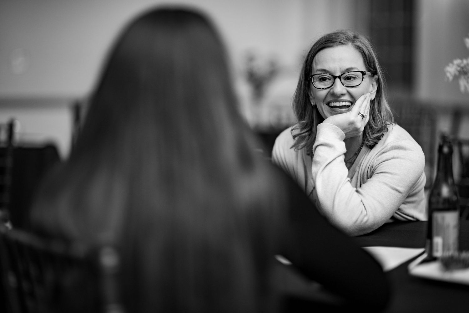 People sharing laughter and conversation at formal indoor gathering.