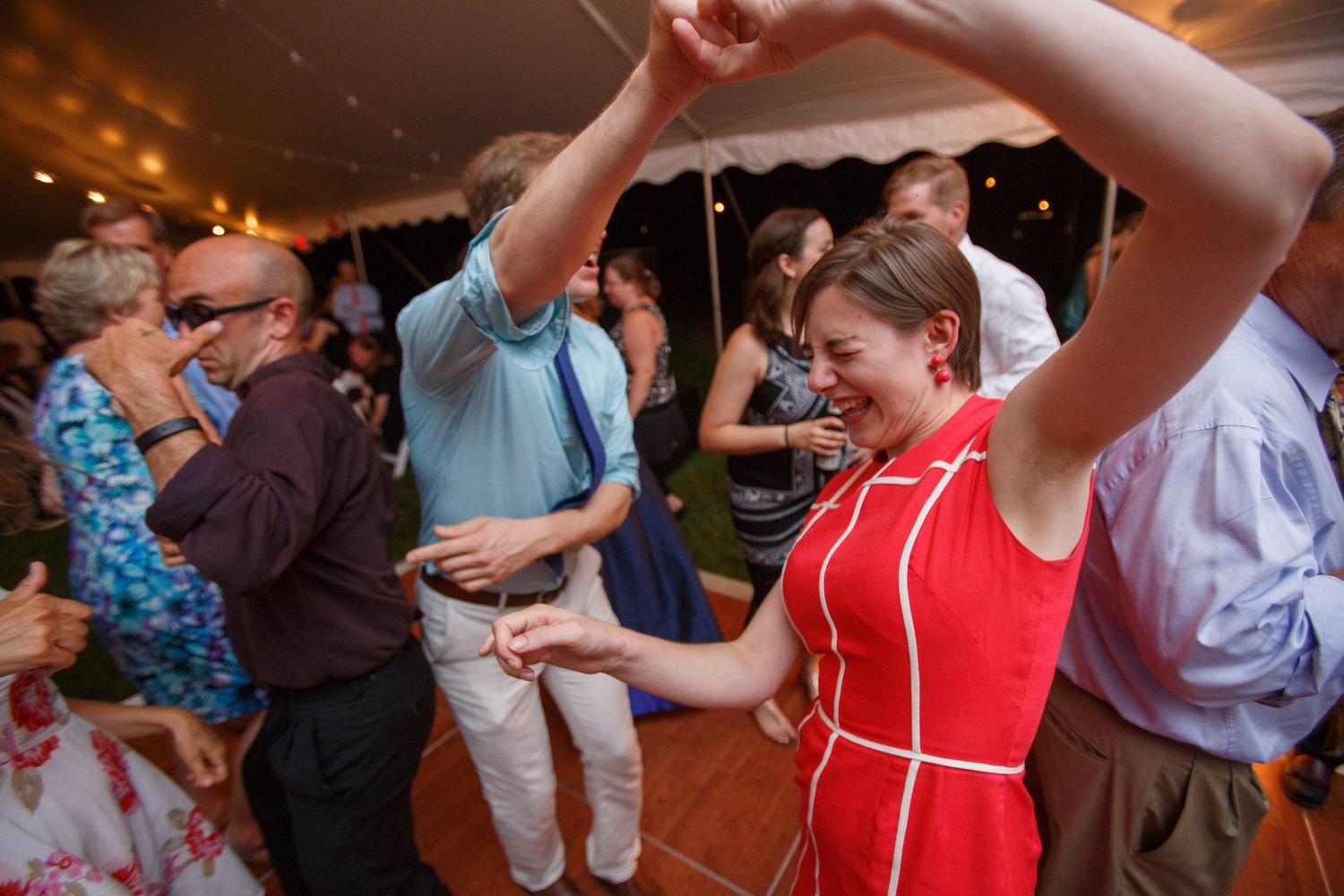 Celebration guests dancing and having fun at a festive reception with warm lighting.