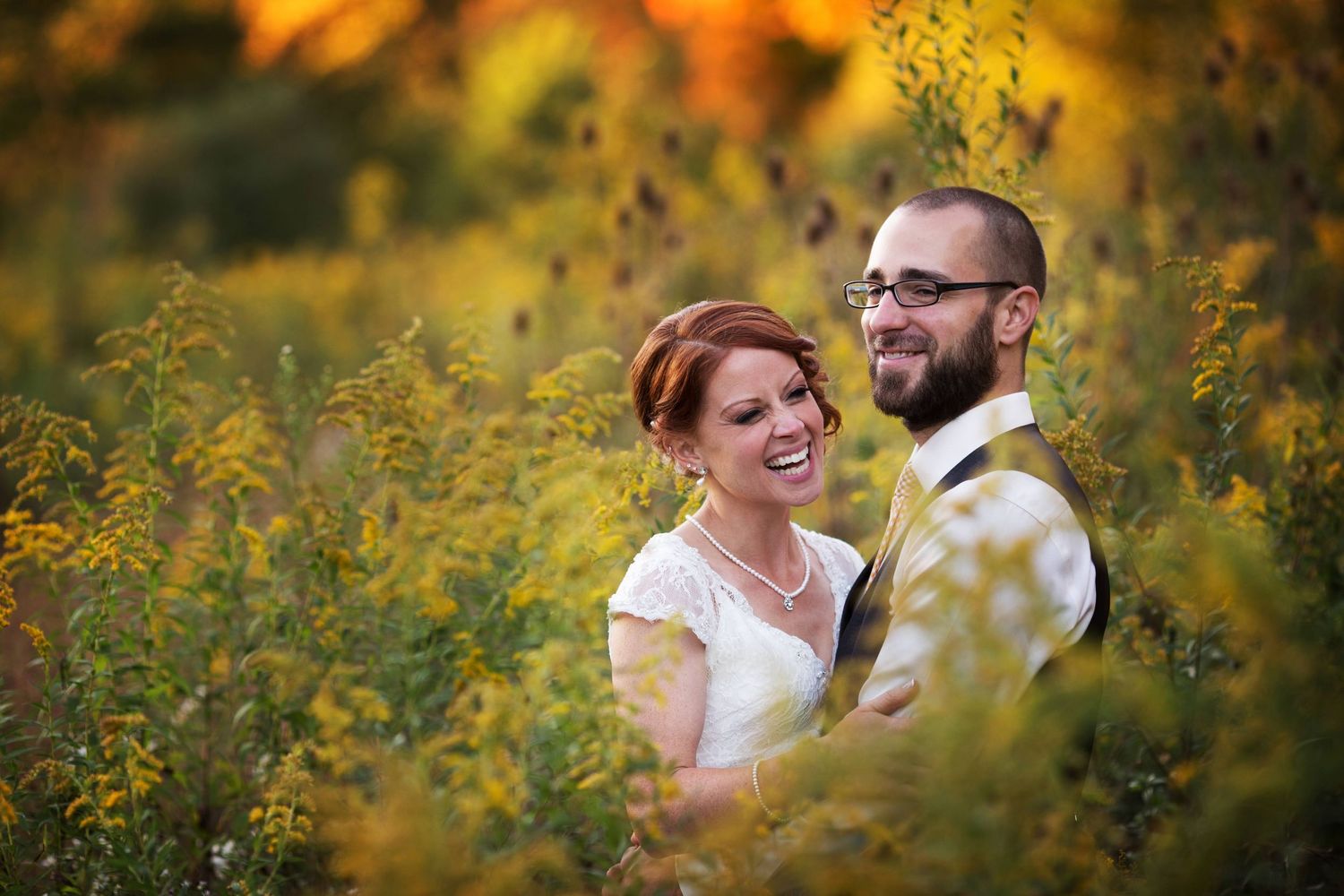Romantic couple embracing in a field of wildflowers during golden hour.