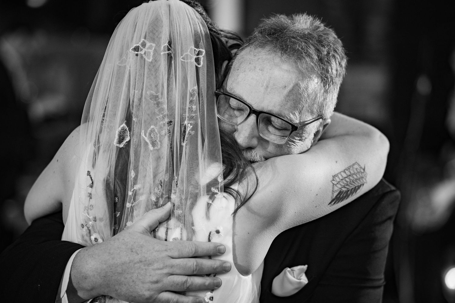 A bride and an emotional guest share a heartfelt hug during a wedding reception.