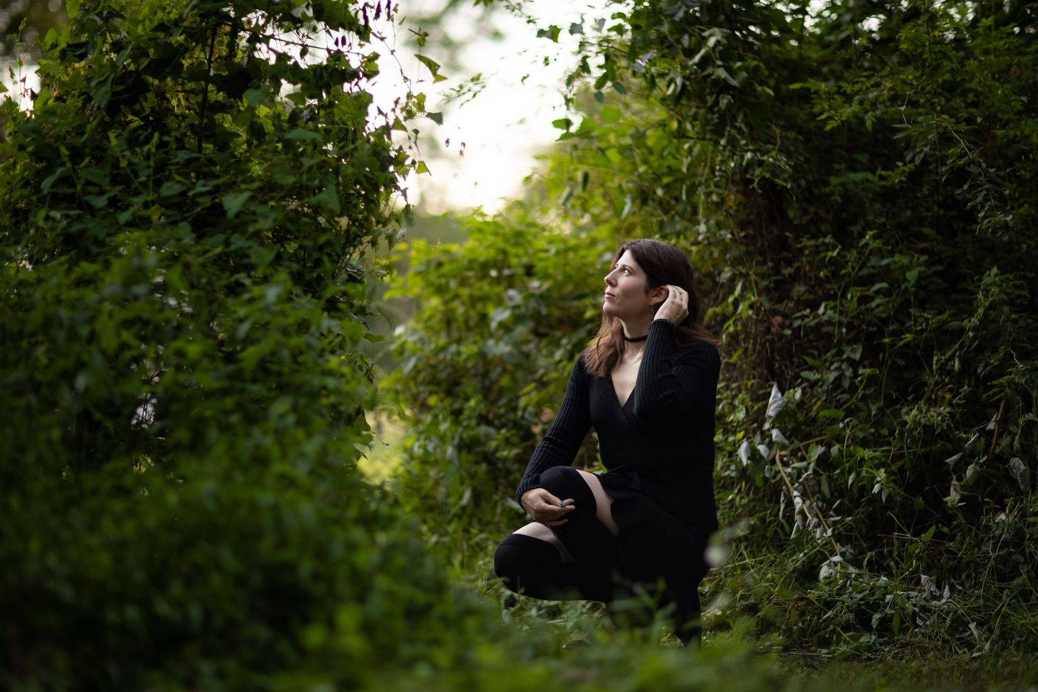 Two people share a romantic moment in a lush garden setting as sunlight filters through the greenery.
