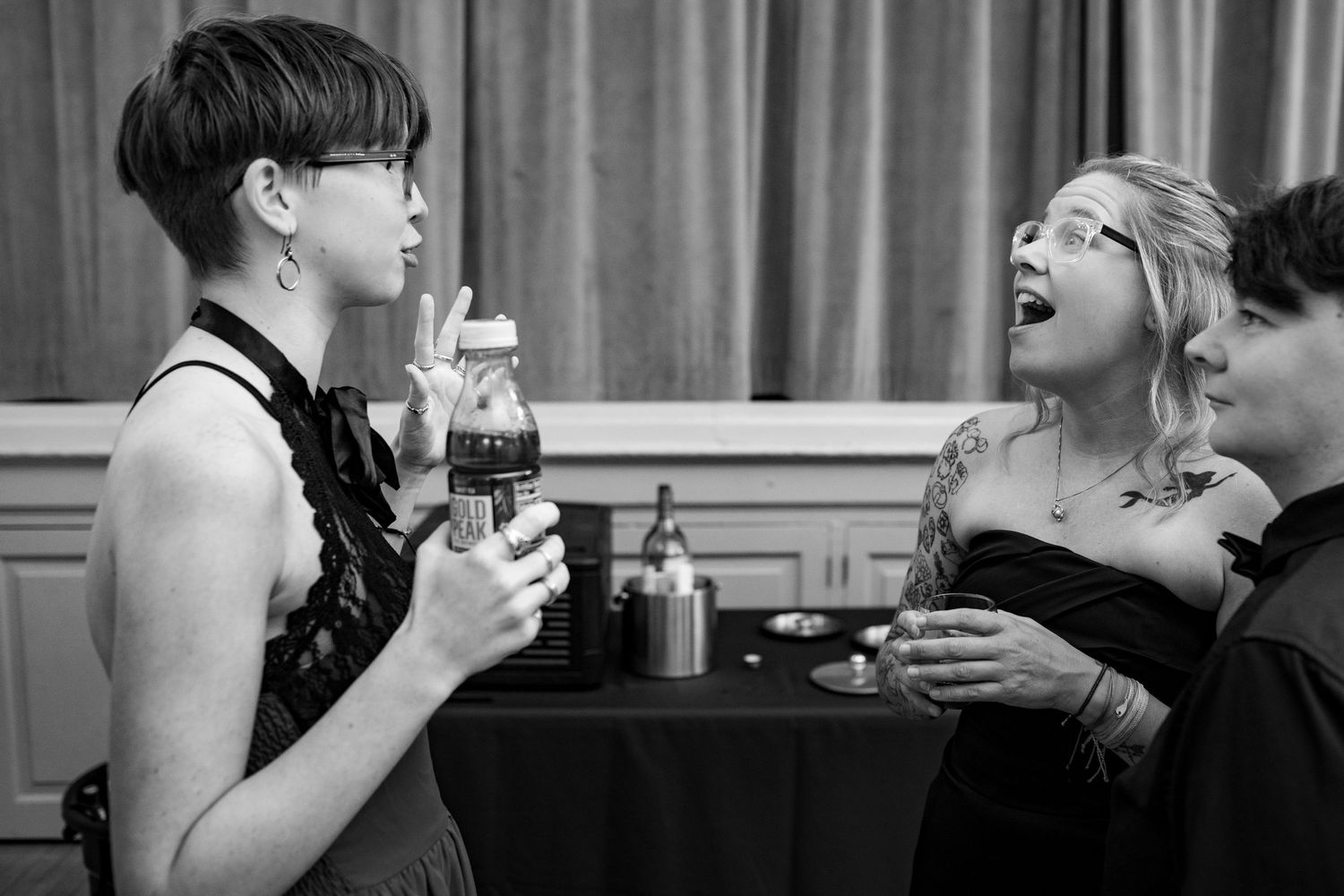 People enjoying drinks and laughter at a social gathering with cocktail glasses in hand.