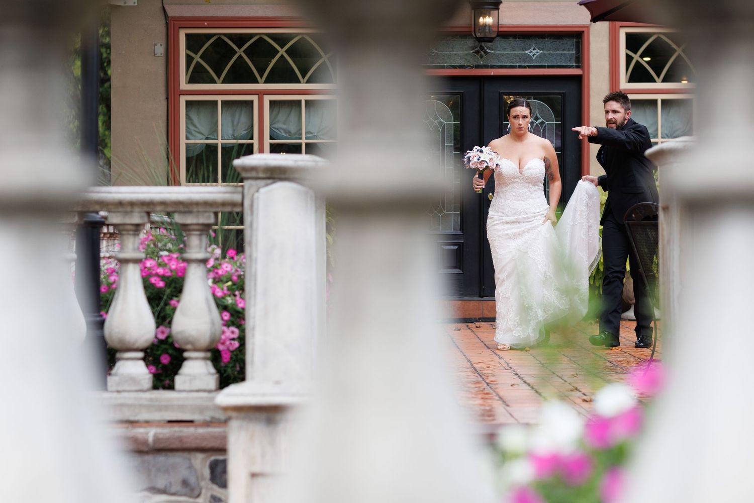 A bride and groom share a romantic moment together in a garden setting with pink flowers in the foreground.