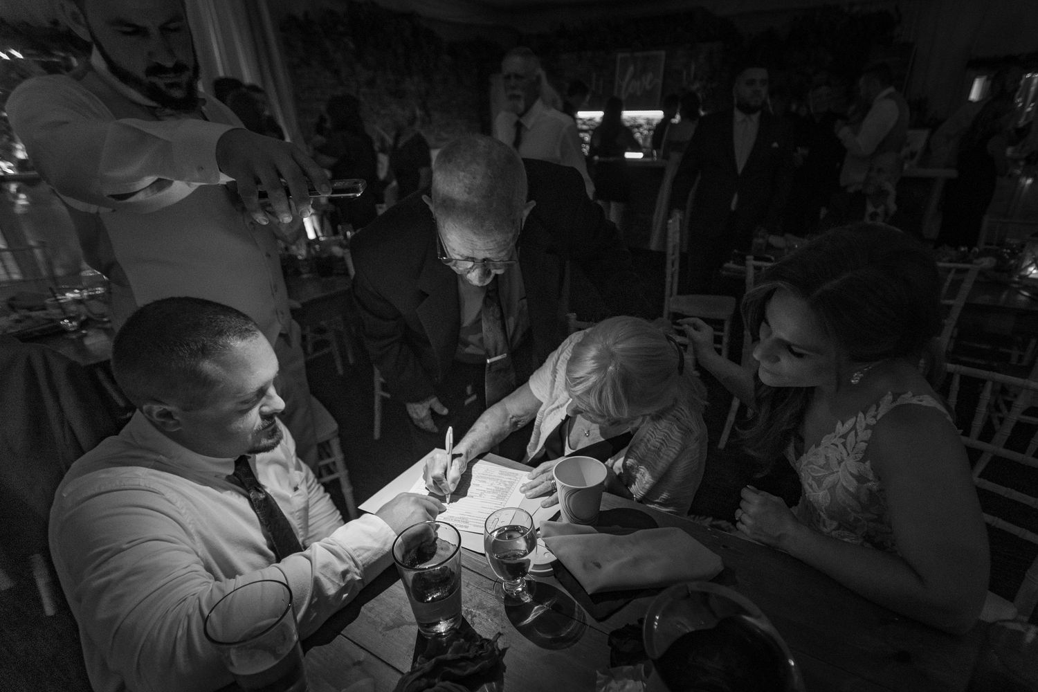 A series of black and white photos showing people gathered in an indoor setting engaging in activities.