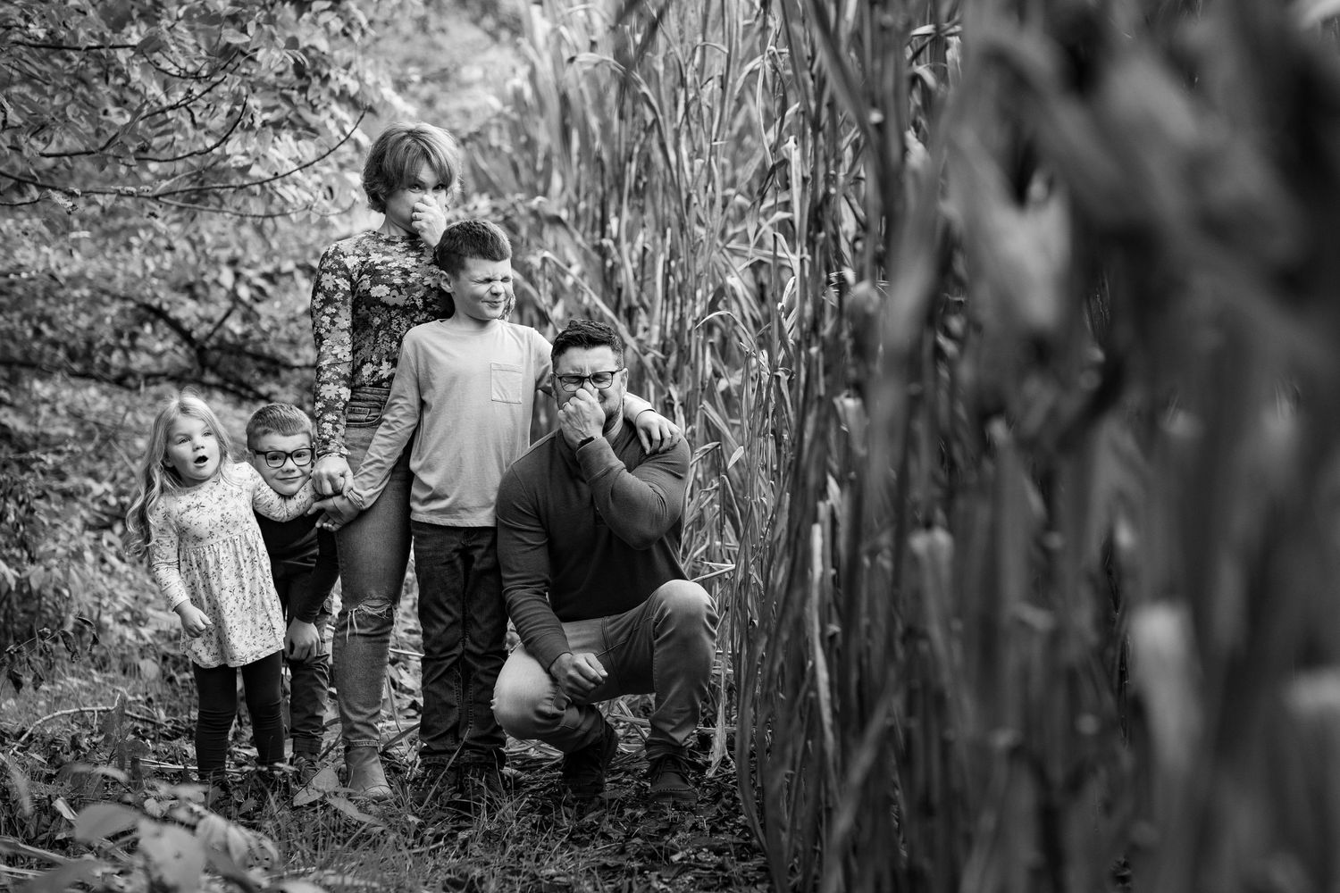 Black and white photo of people walking through corn stalks.