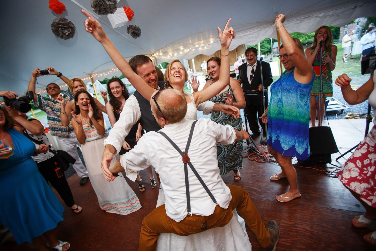Energetic wedding reception dance party with guests celebrating on the dance floor.