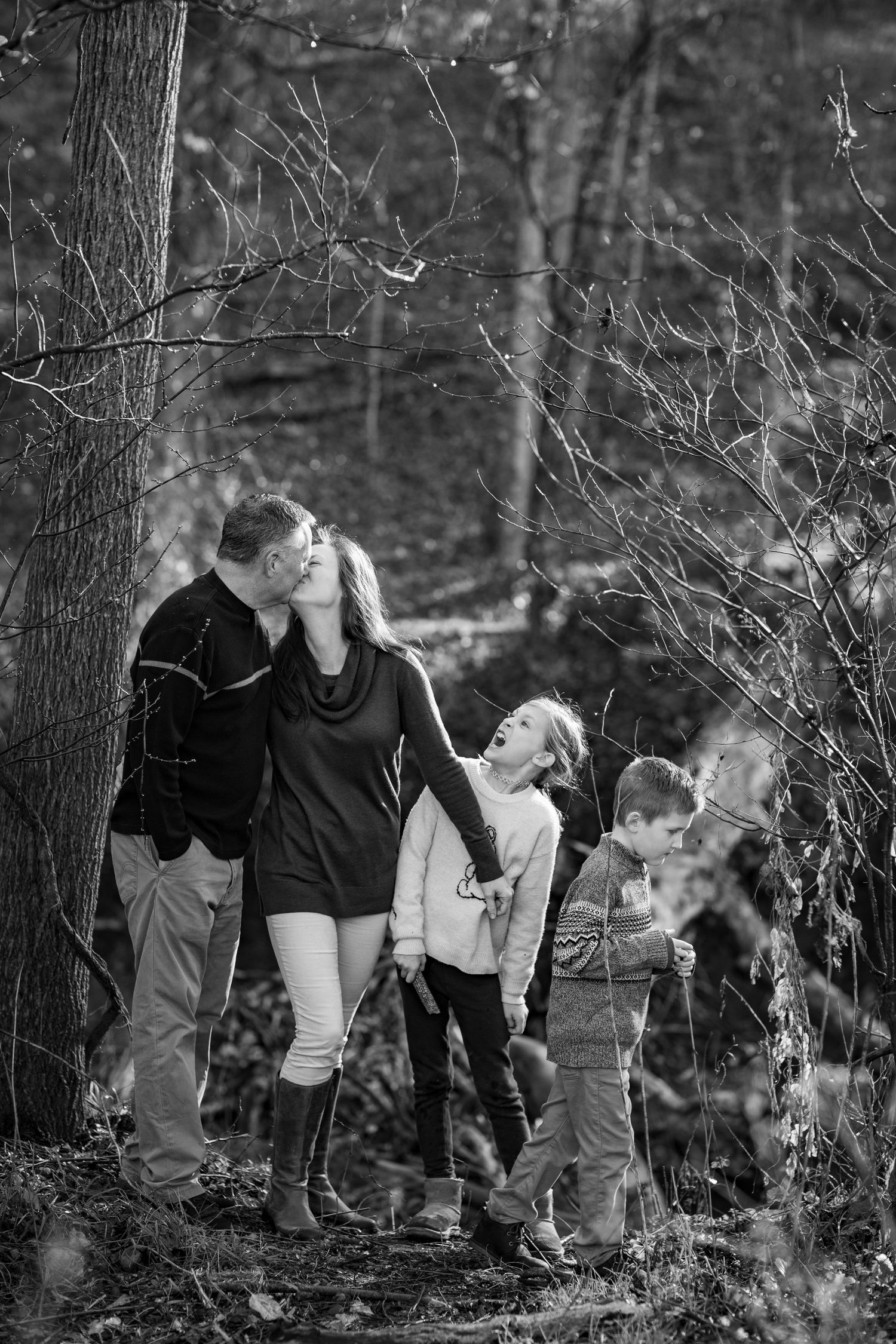 Black and white candid photo of group exploring together in wooded forest path.