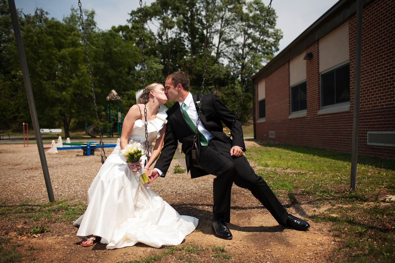 A bride and groom on a swing kissing in their formal wear