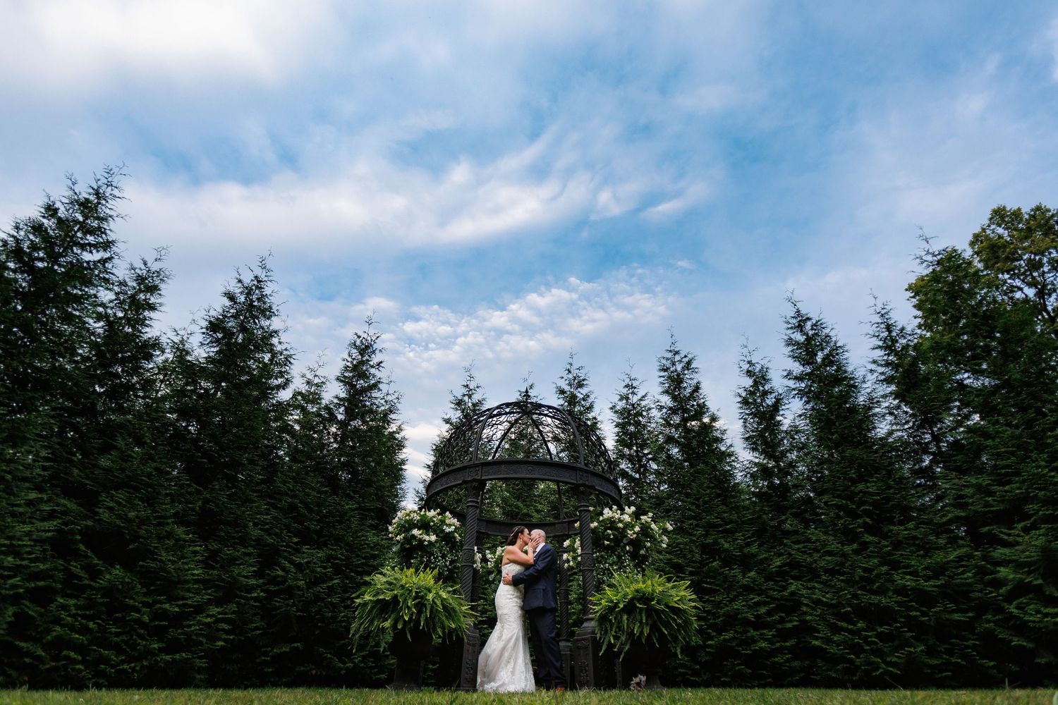 A scenic wedding ceremony site with evergreen trees and blue sky in the background.