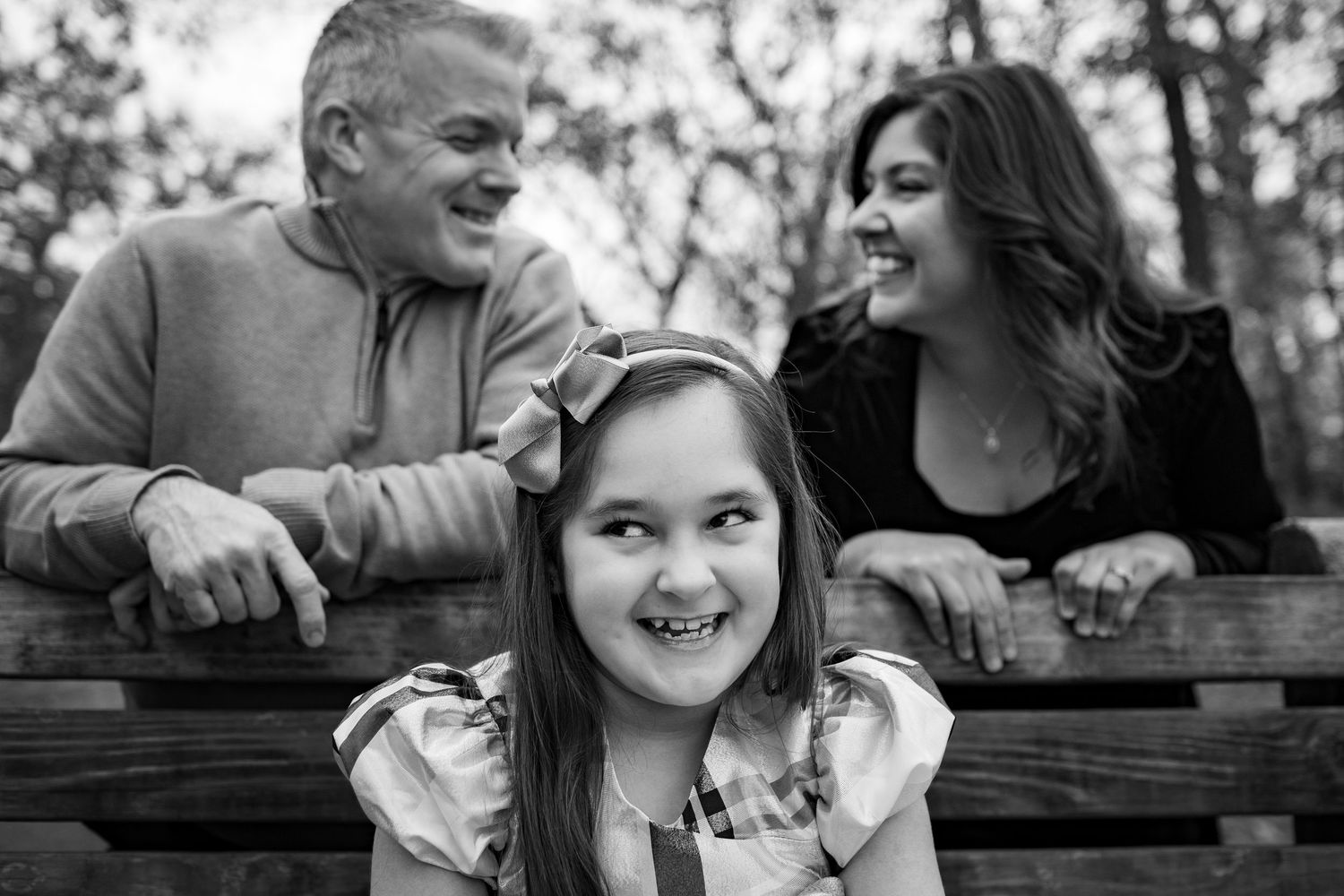 A series of black and white photos showing a family sharing joyful moments together on a park bench.