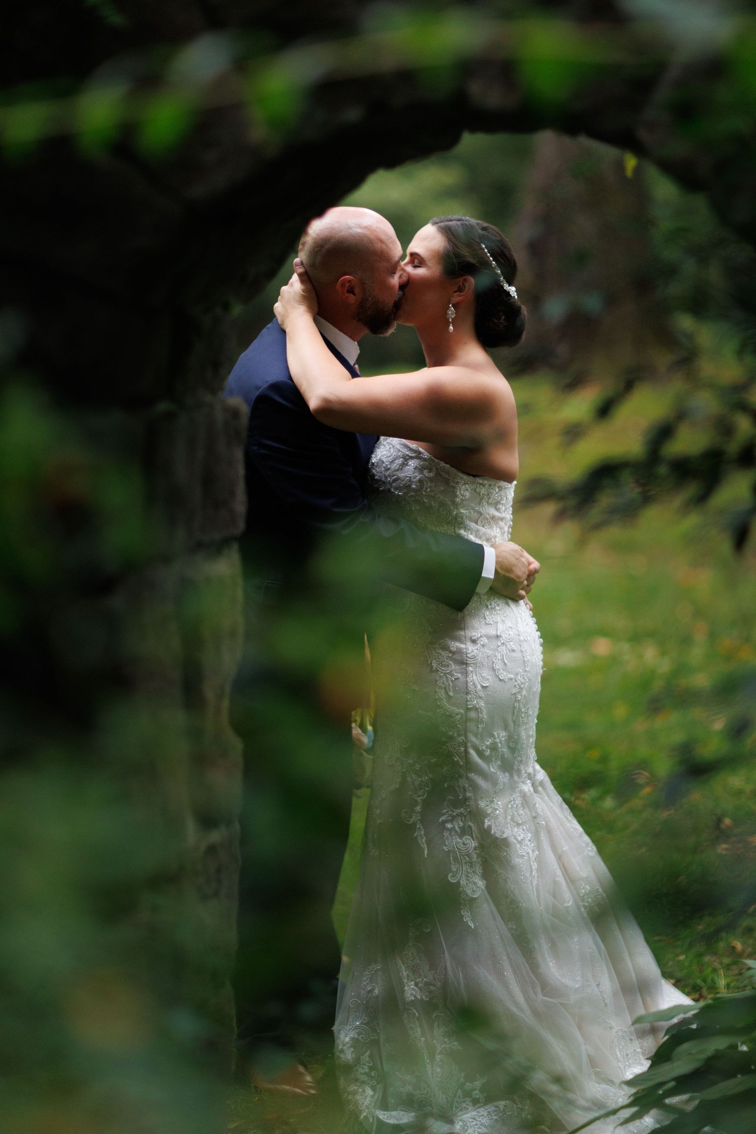 A romantic outdoor wedding moment with a couple embracing in a garden setting with lush greenery.