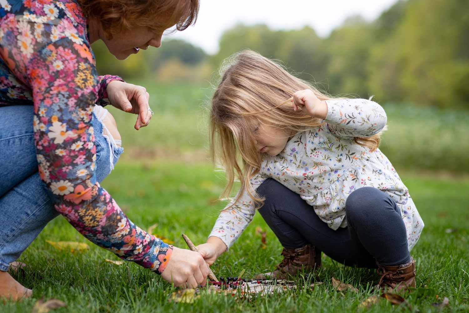 Close-up view of someone collecting small natural objects in a grassy outdoor setting.