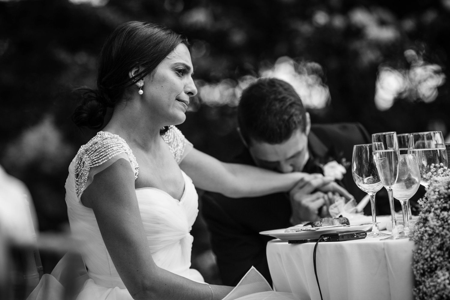 groom kissing his wife's hand while she cries at the reception