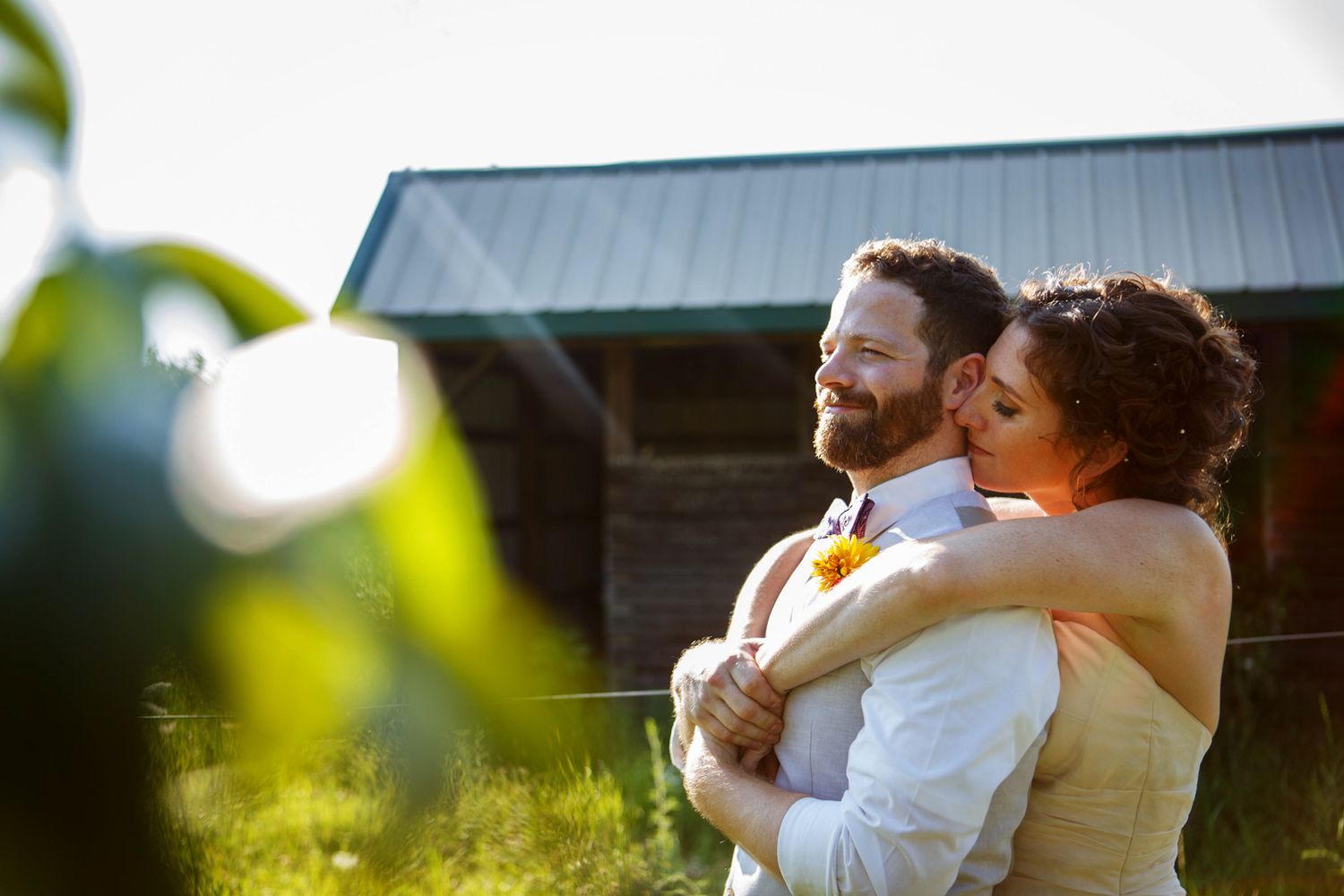 A bride is leaning over the groom's shoulder and whispering into his ear