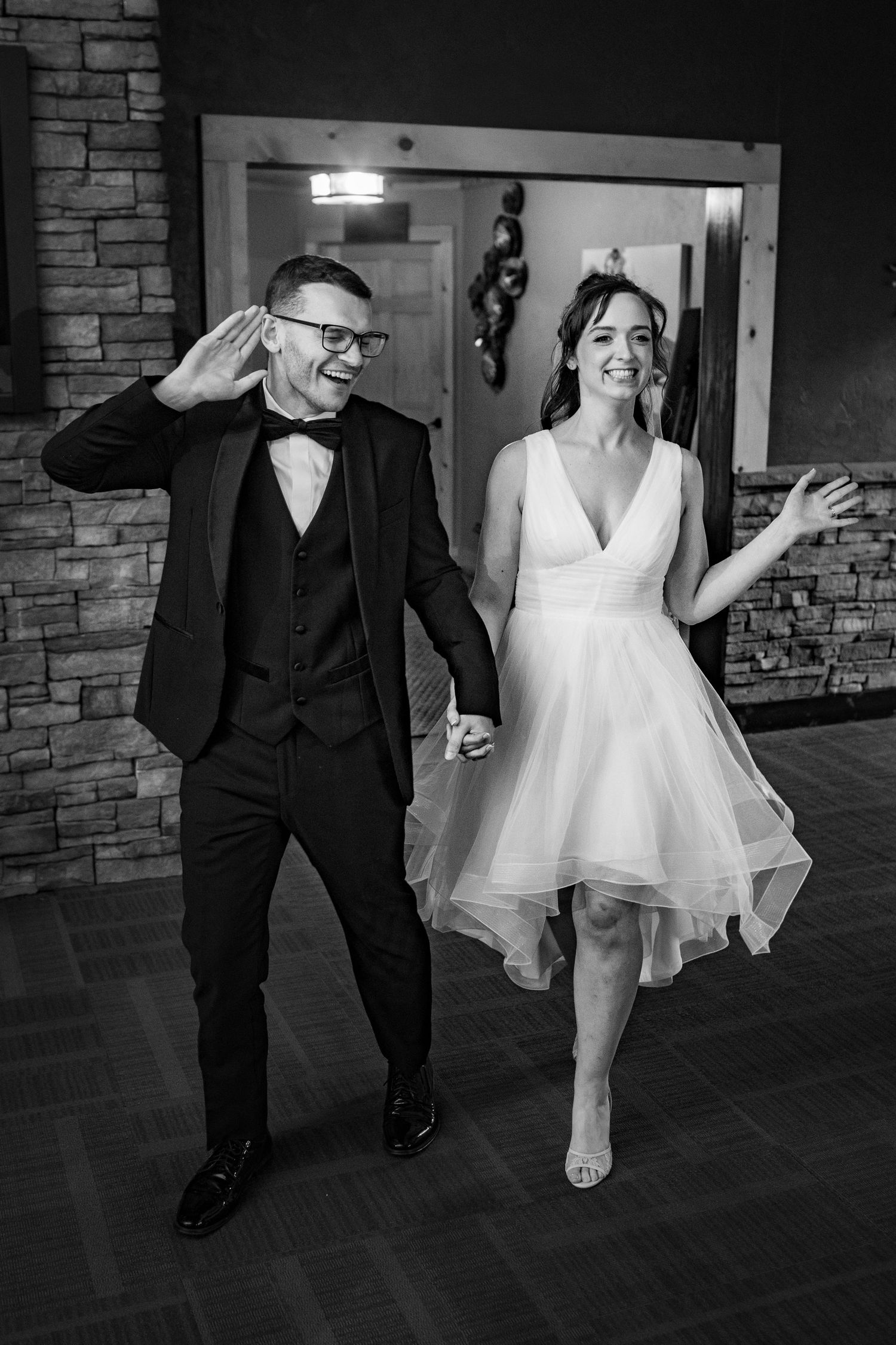 A joyful bride and groom make a grand entrance at their wedding reception.