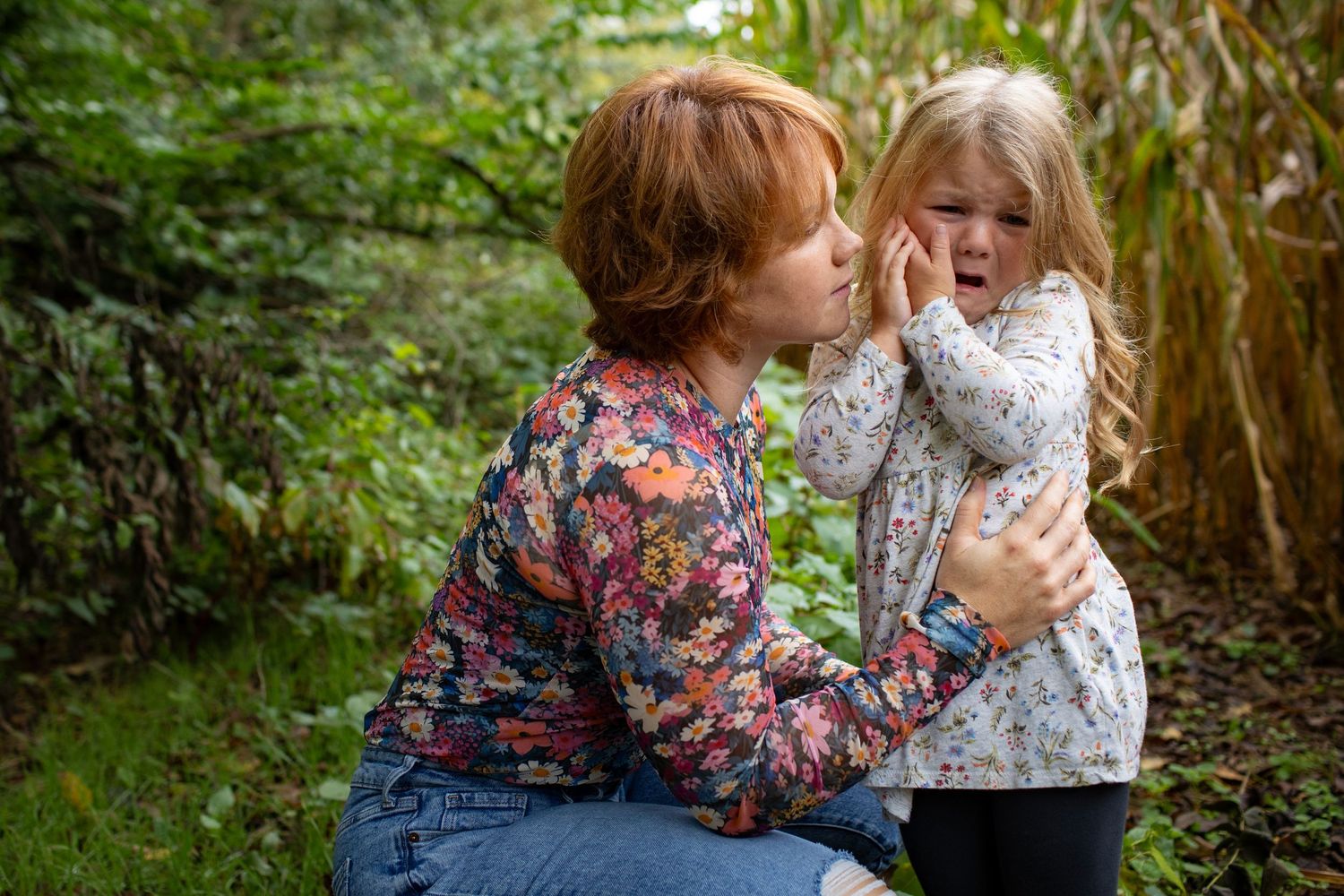 Two people sharing an affectionate moment outdoors near autumn foliage.