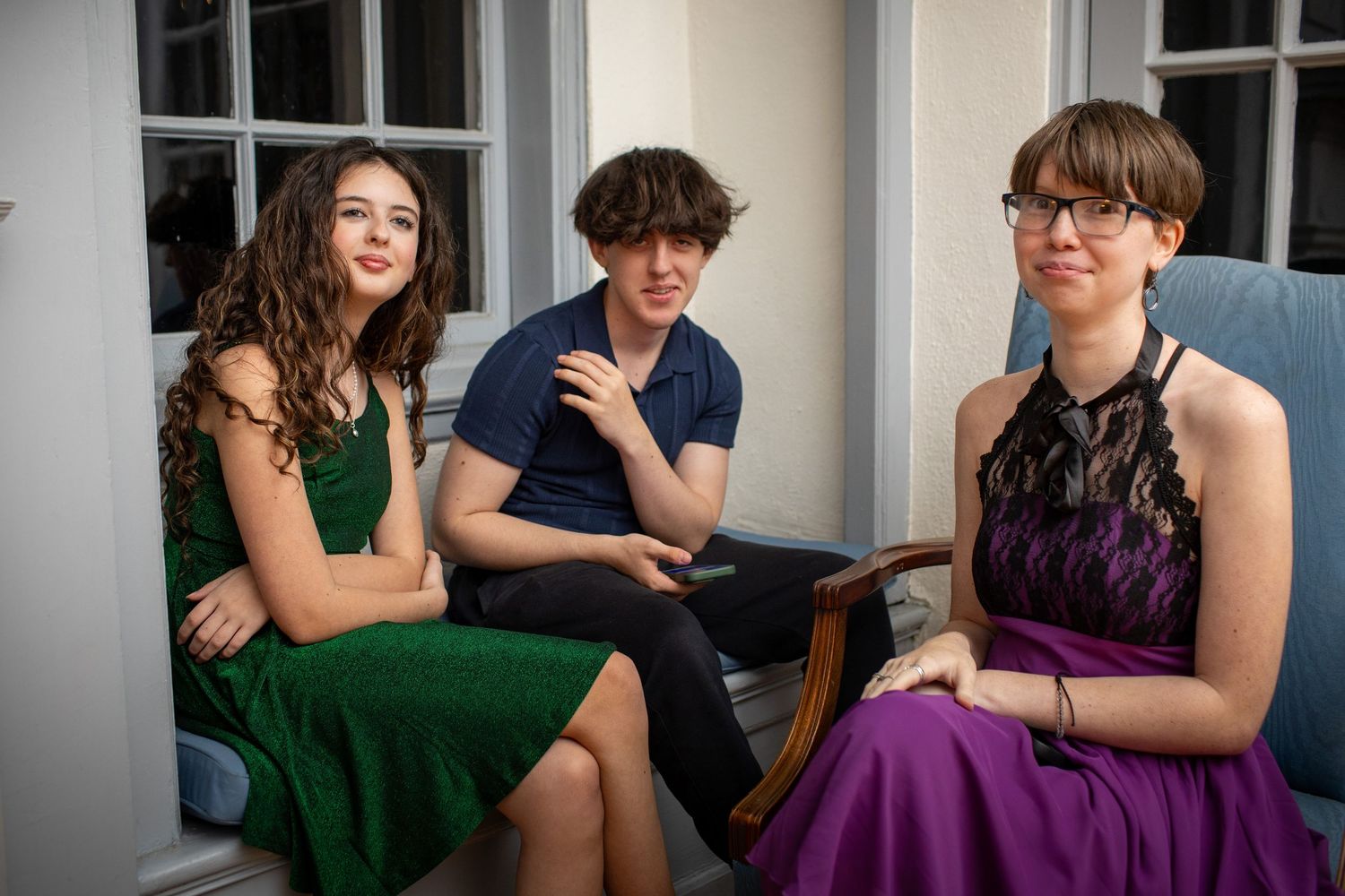 Group photo in an elegant room with people wearing colorful formal dresses in purple and green.