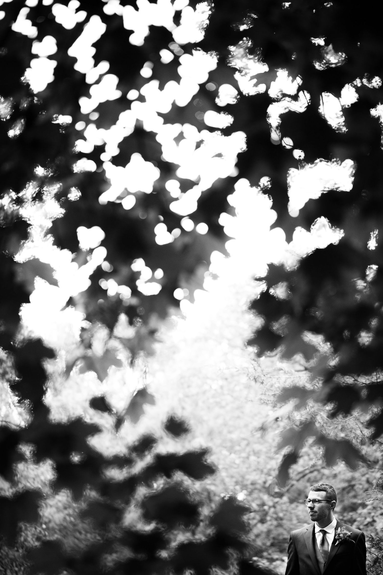 A dramatic black and white photograph of a cloudy sky with bright sunlight filtering through scattered clouds.