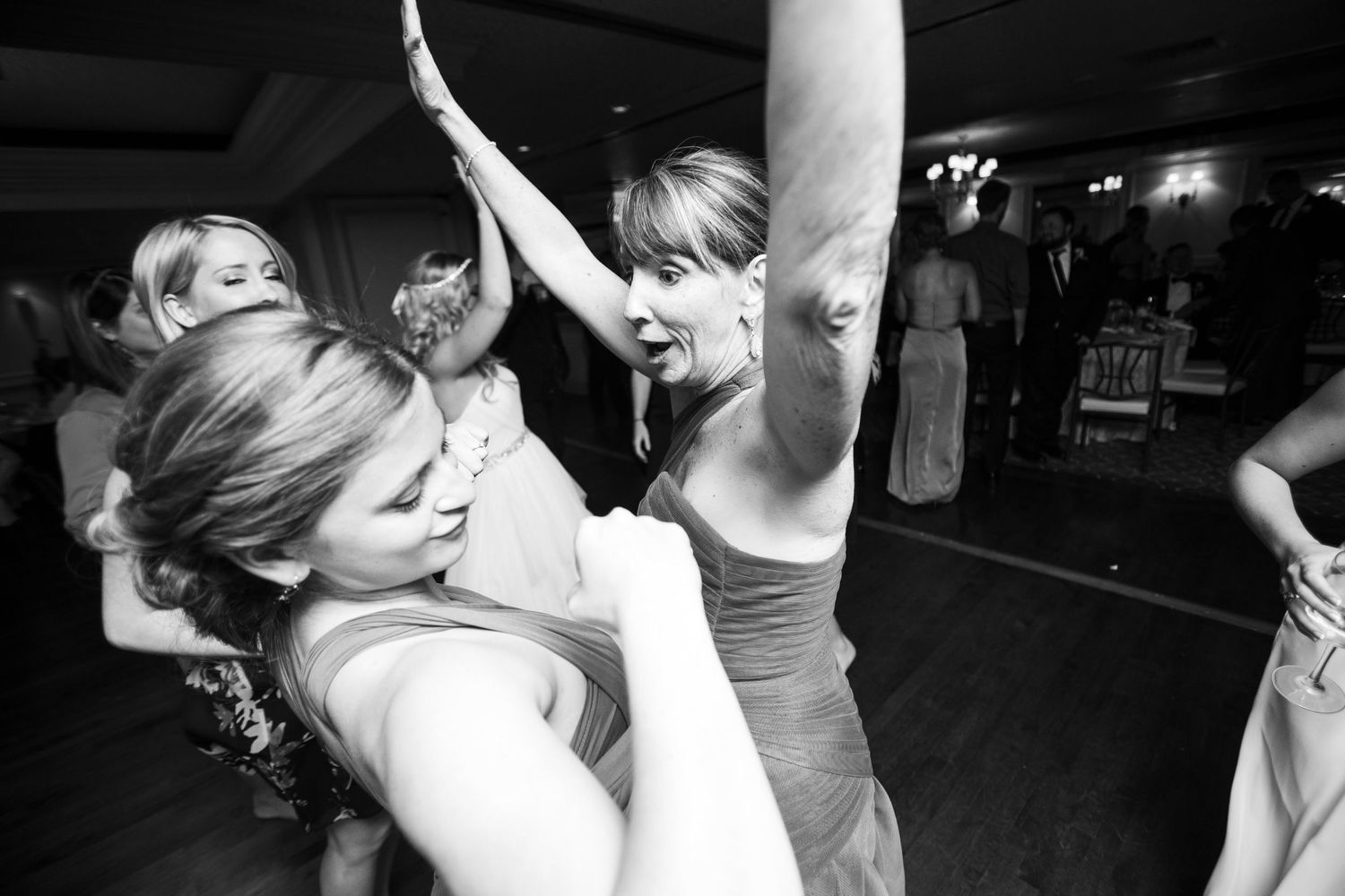 People dancing energetically at a black and white wedding reception on a dark dance floor.